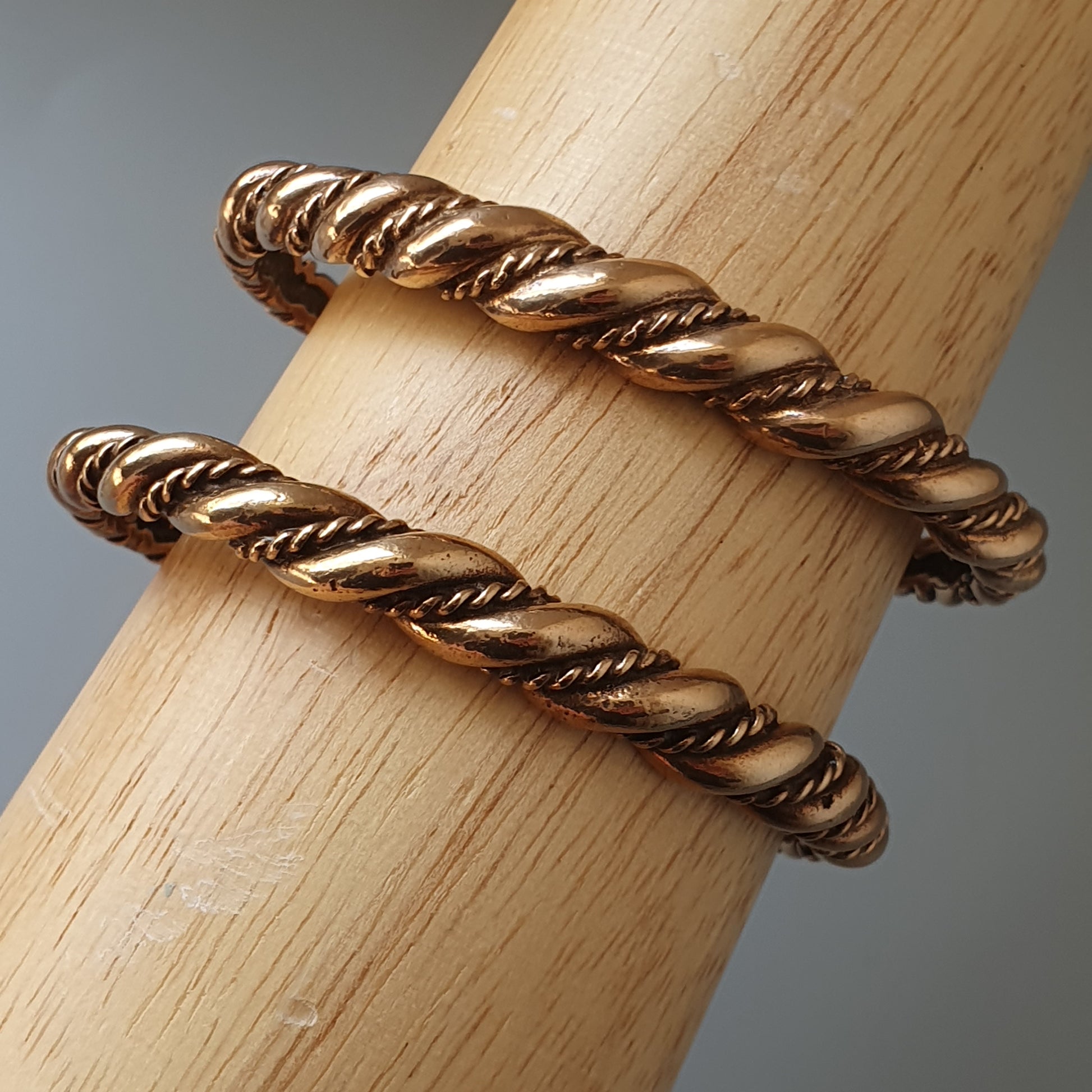 Twisted gold metal bracelet or bangle with a rope-like design.