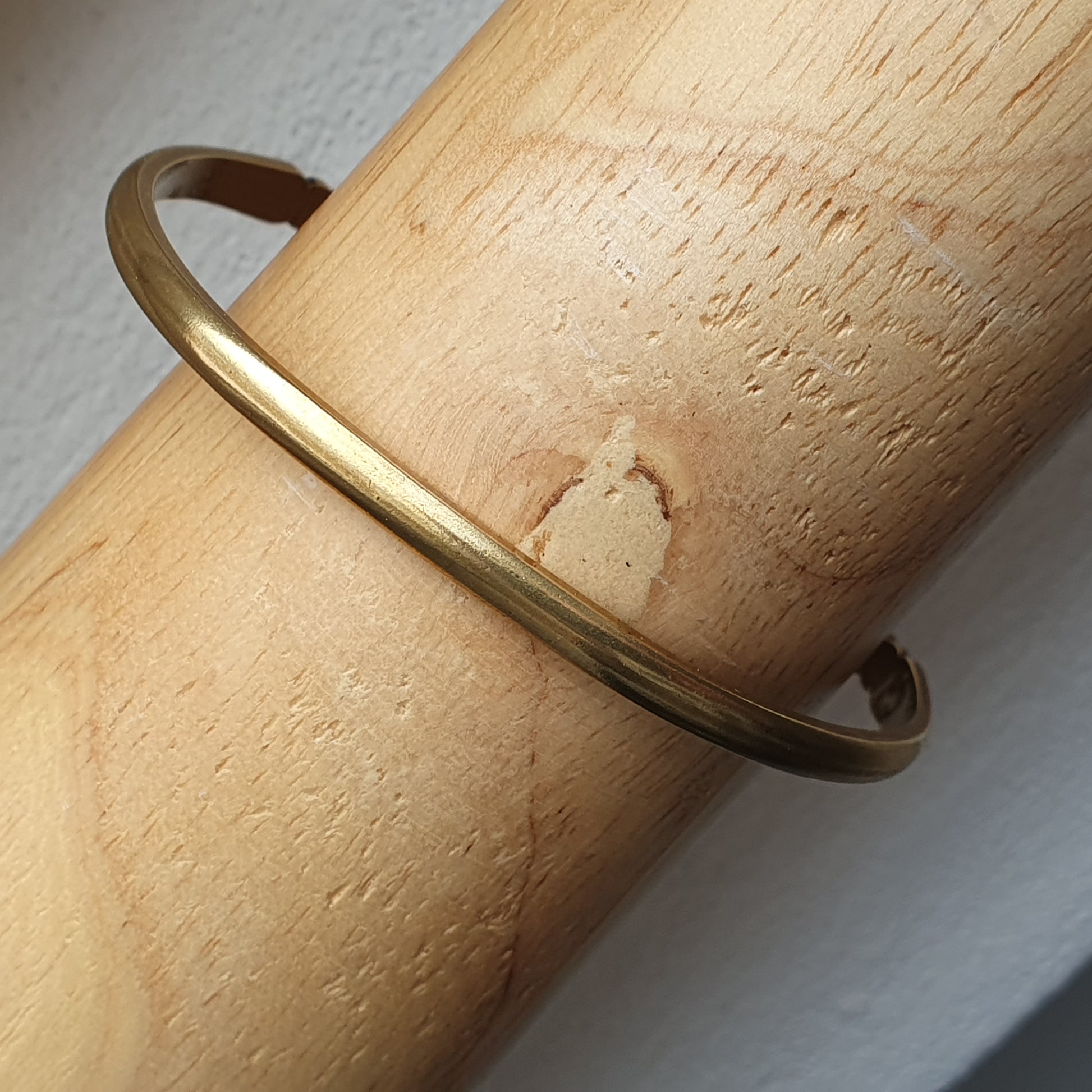 Gold bangle bracelet worn on a wrist.