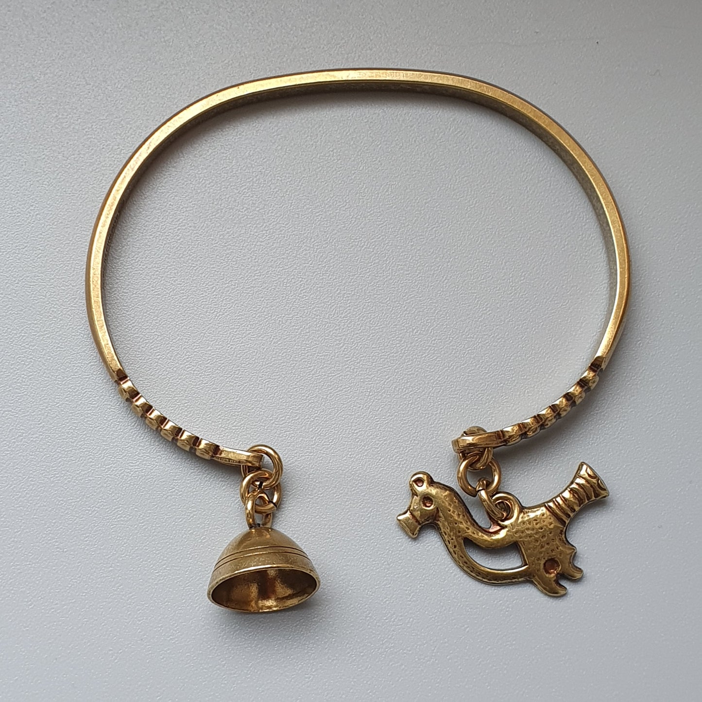 Gold bracelet with dangling bell and animal-shaped charms.