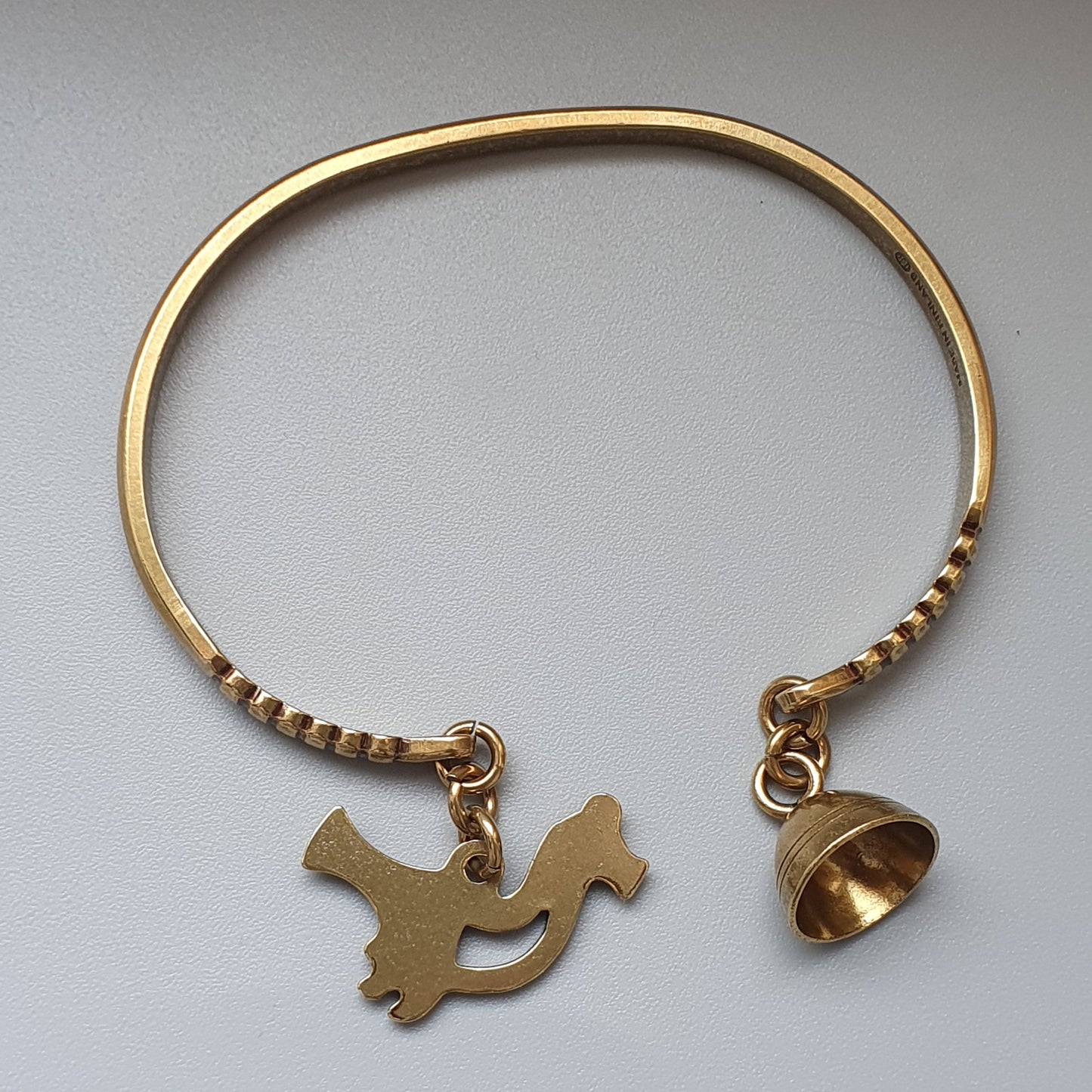 Gold bracelet with a bird charm and a bell charm.