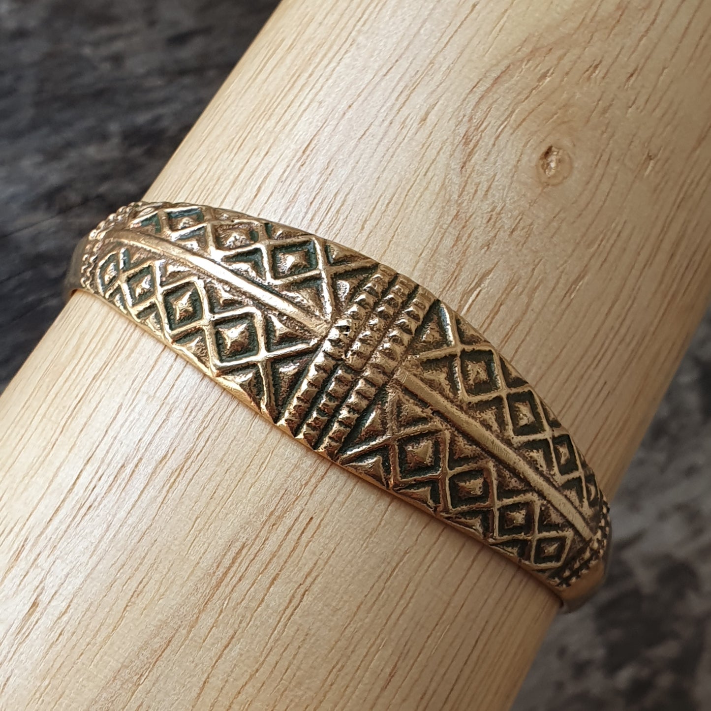 Gold-toned ring with intricate geometric patterns and textures.