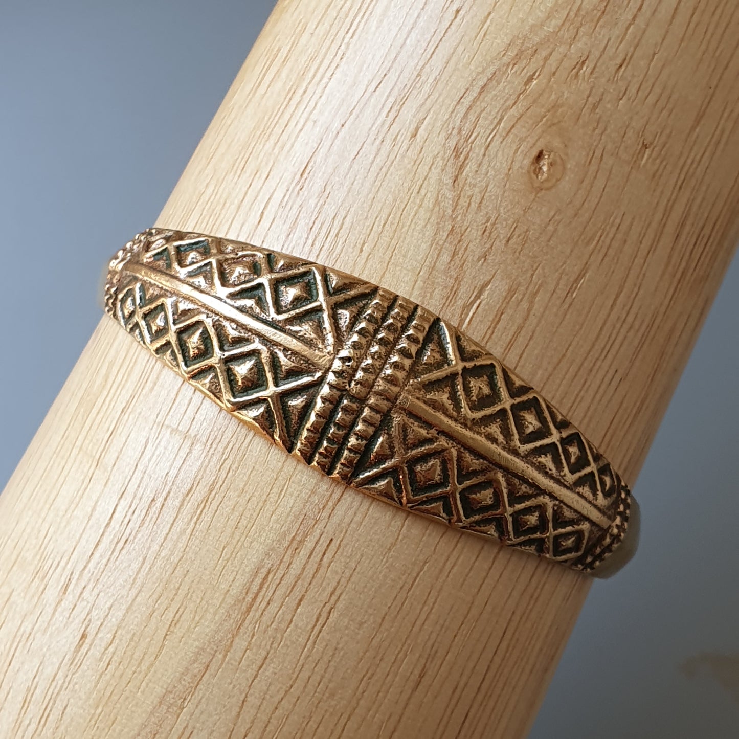 Gold-toned metal bracelet with intricate geometric patterns.