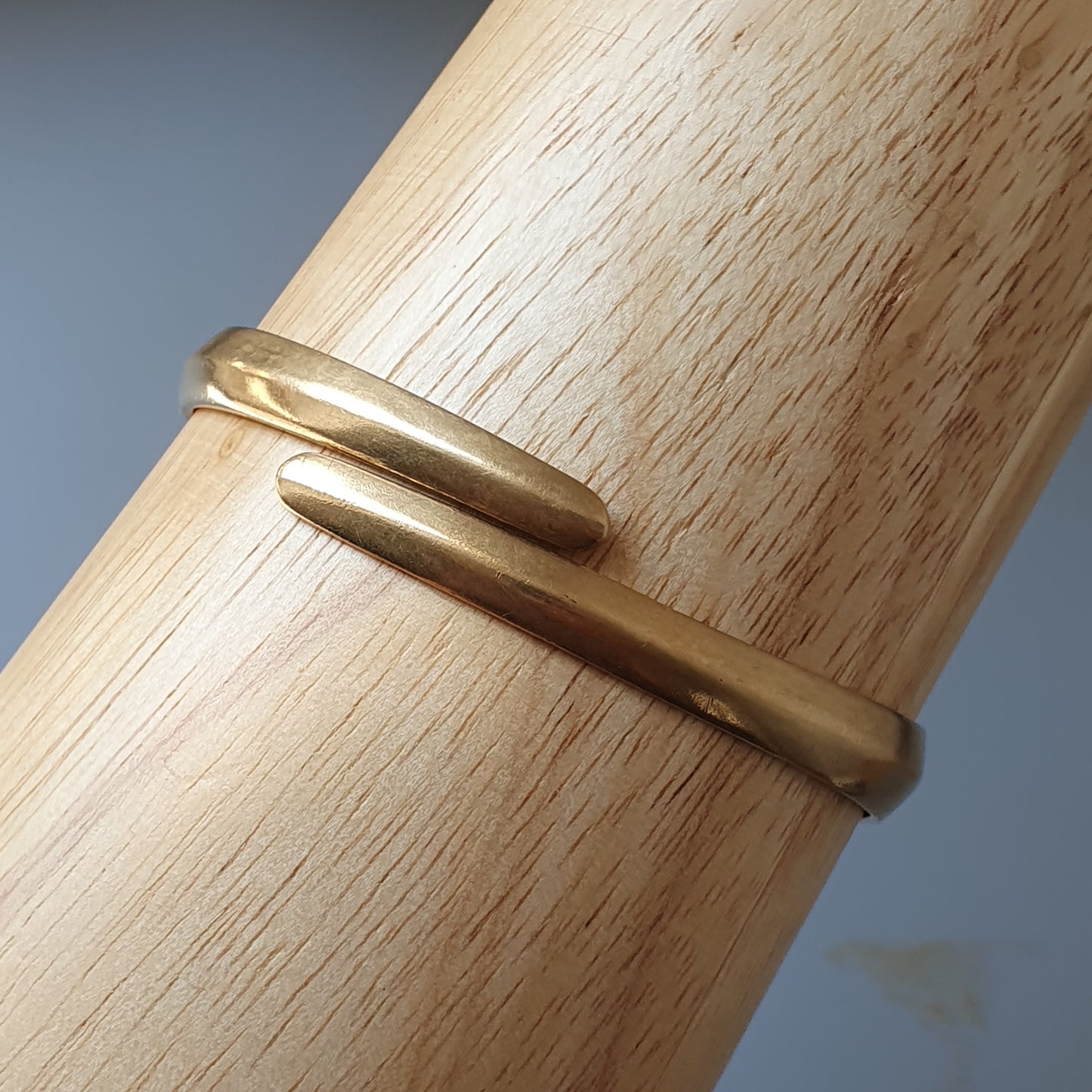 Gold-colored metal ring with a simple, overlapping design.