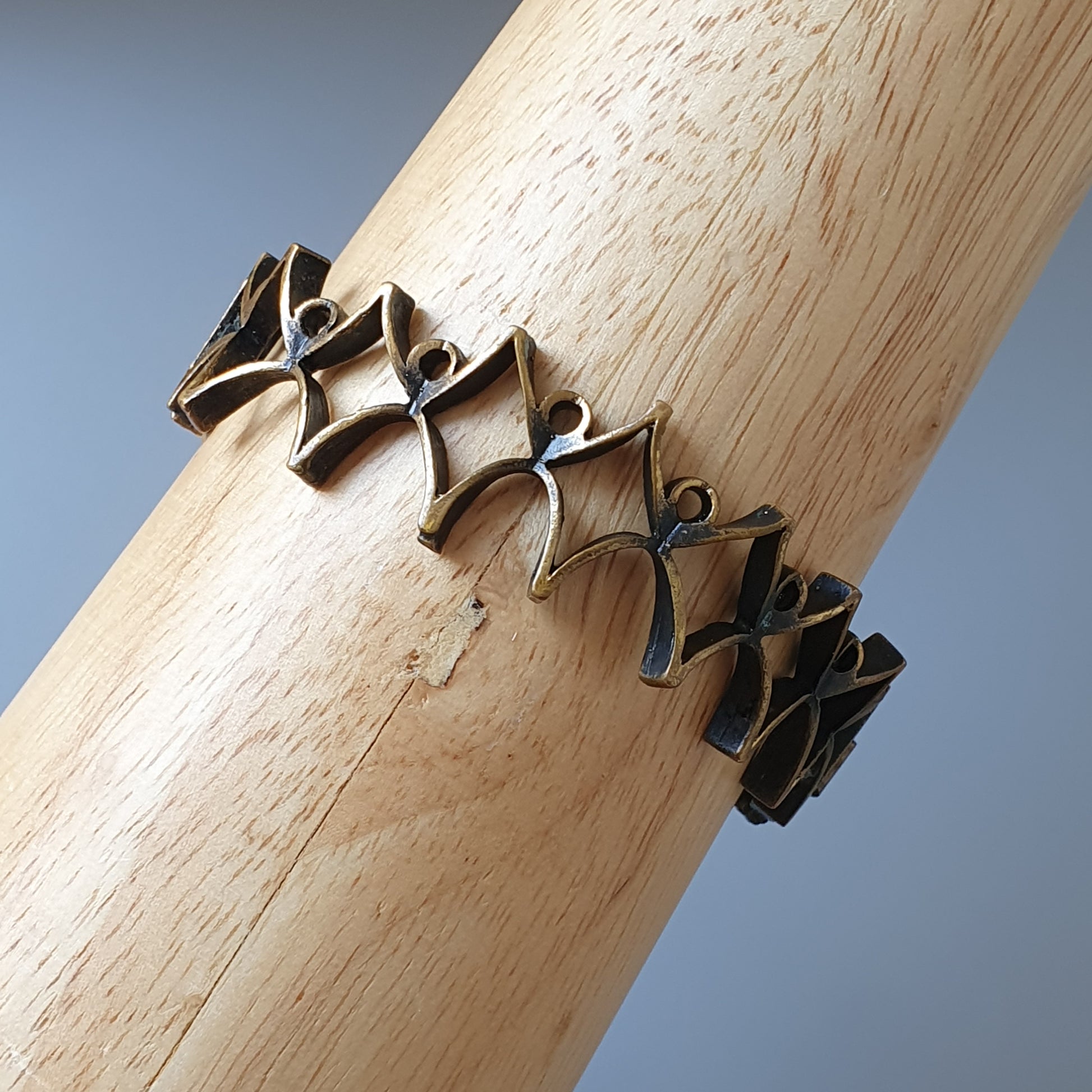 Intricately designed metal bracelet with a zigzag pattern wrapped around a wooden surface.