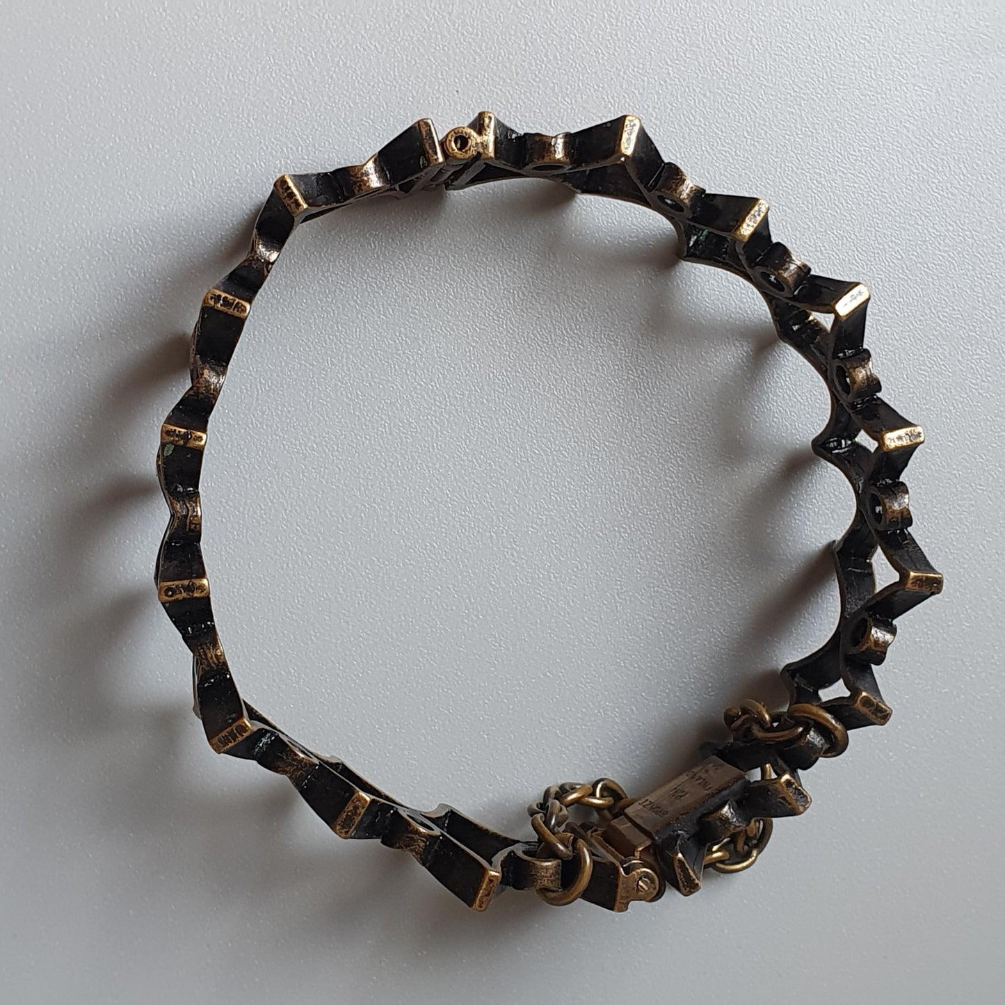 Metallic bracelet with angular, geometric links forming a circular shape.