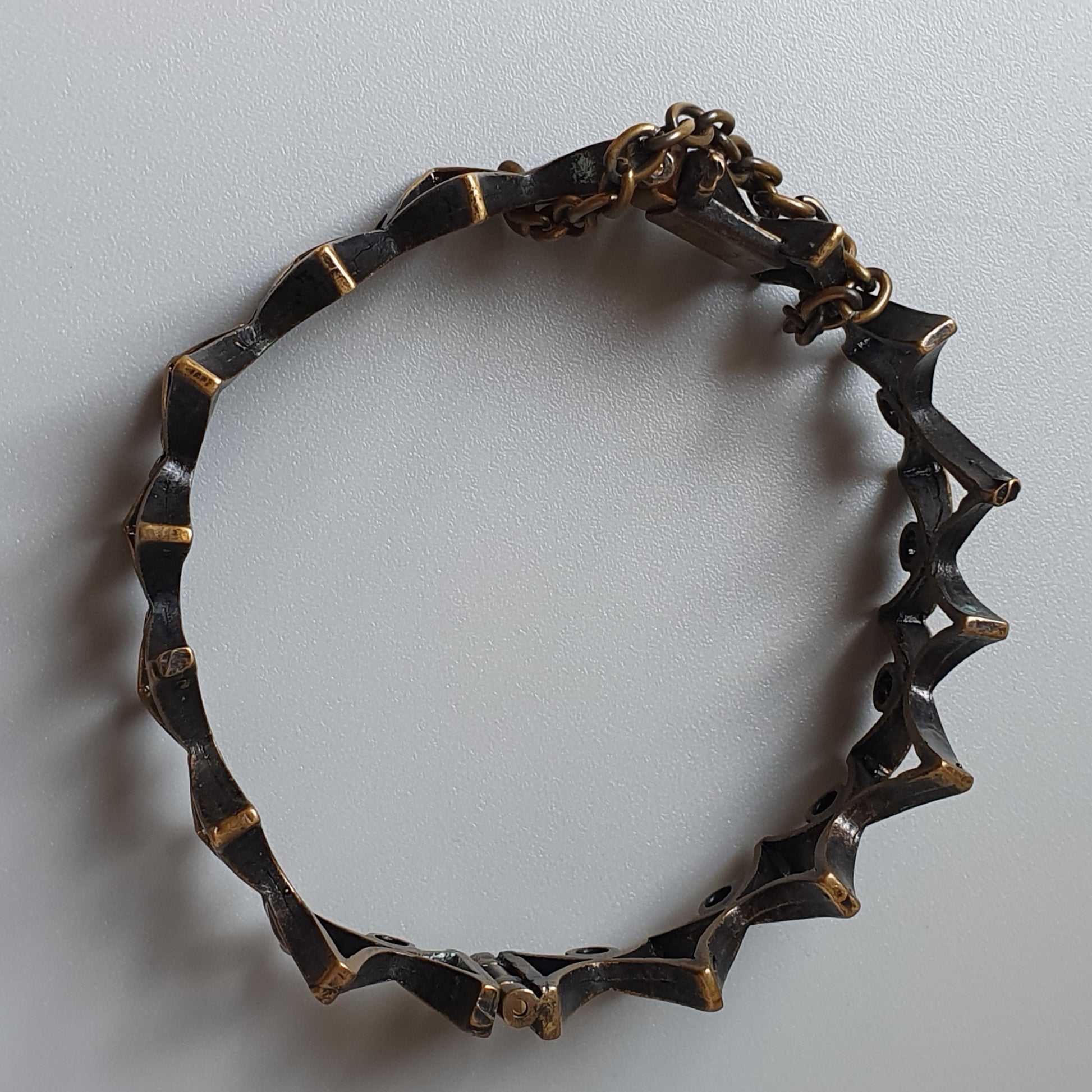 Circular bracelet or bangle with spiky, geometric metal segments.