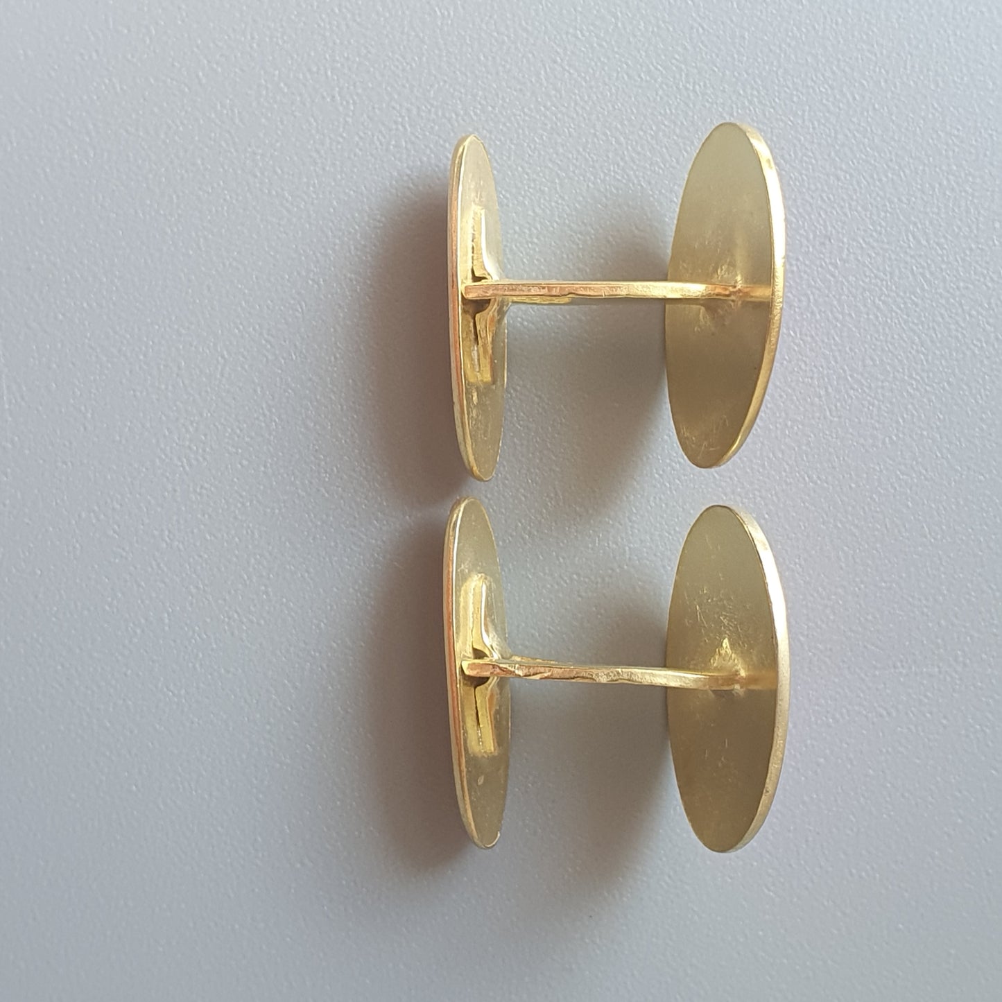 Pair of gold-colored oval cufflinks.