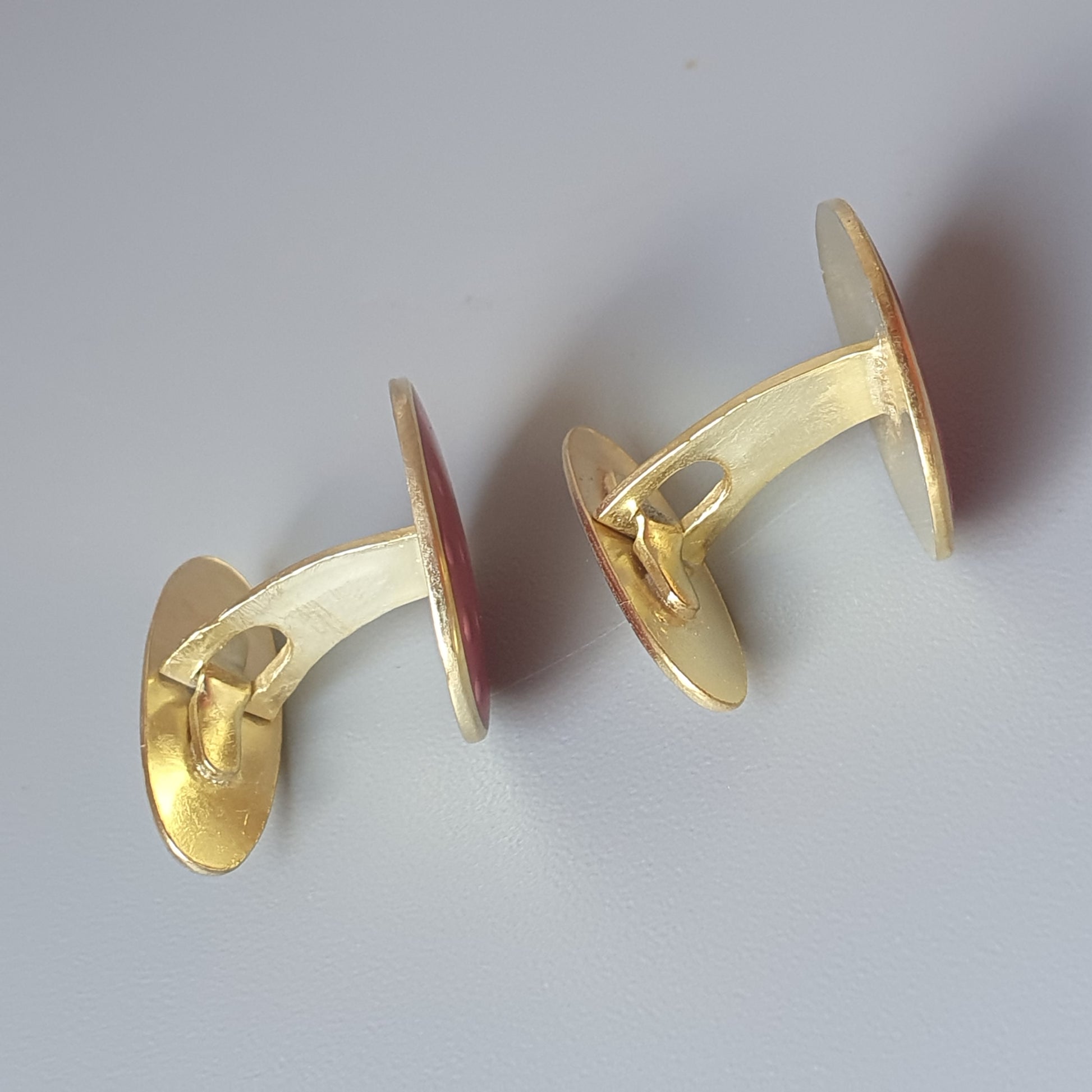 Pair of gold-colored cufflinks with oval-shaped faces and curved bars.