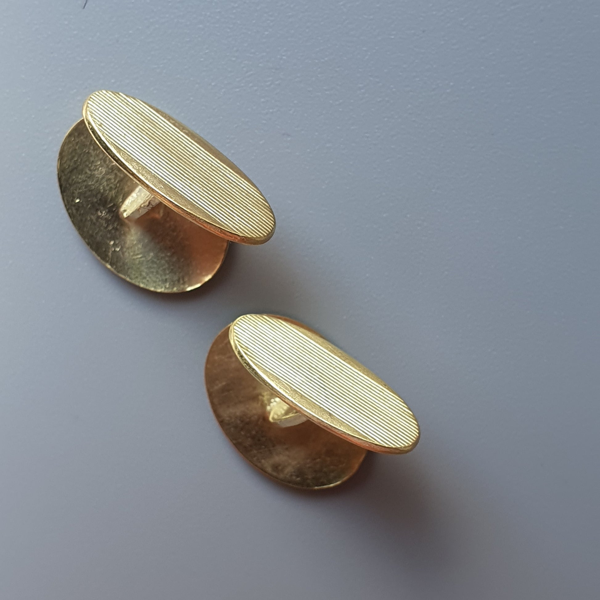 Pair of gold-colored cufflinks with textured circular faces.