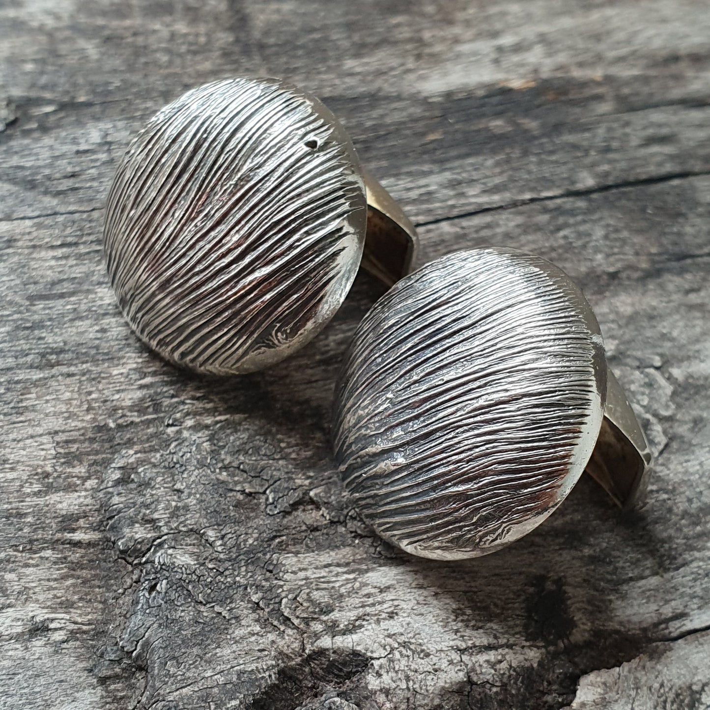 Pair of silver cufflinks with a textured, striated surface design.