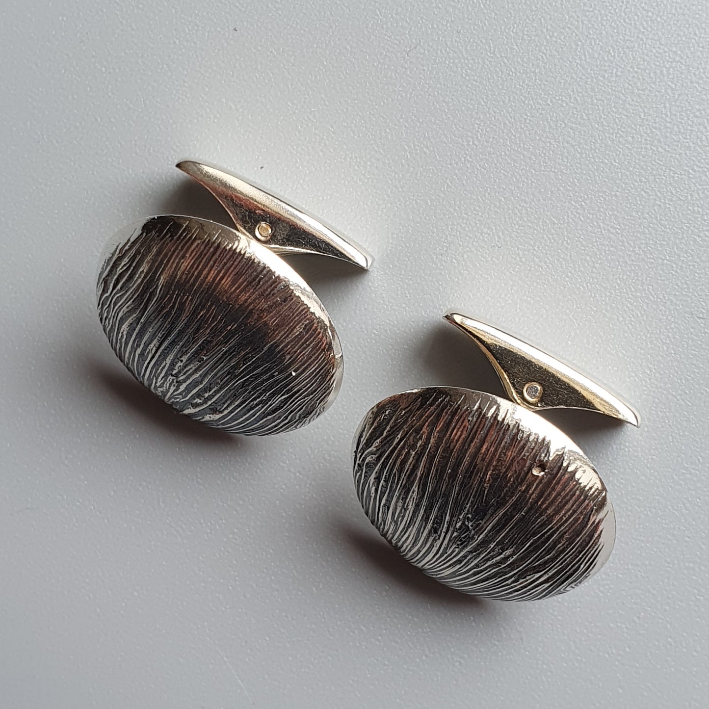 Pair of oval silver cufflinks with textured, etched surfaces.