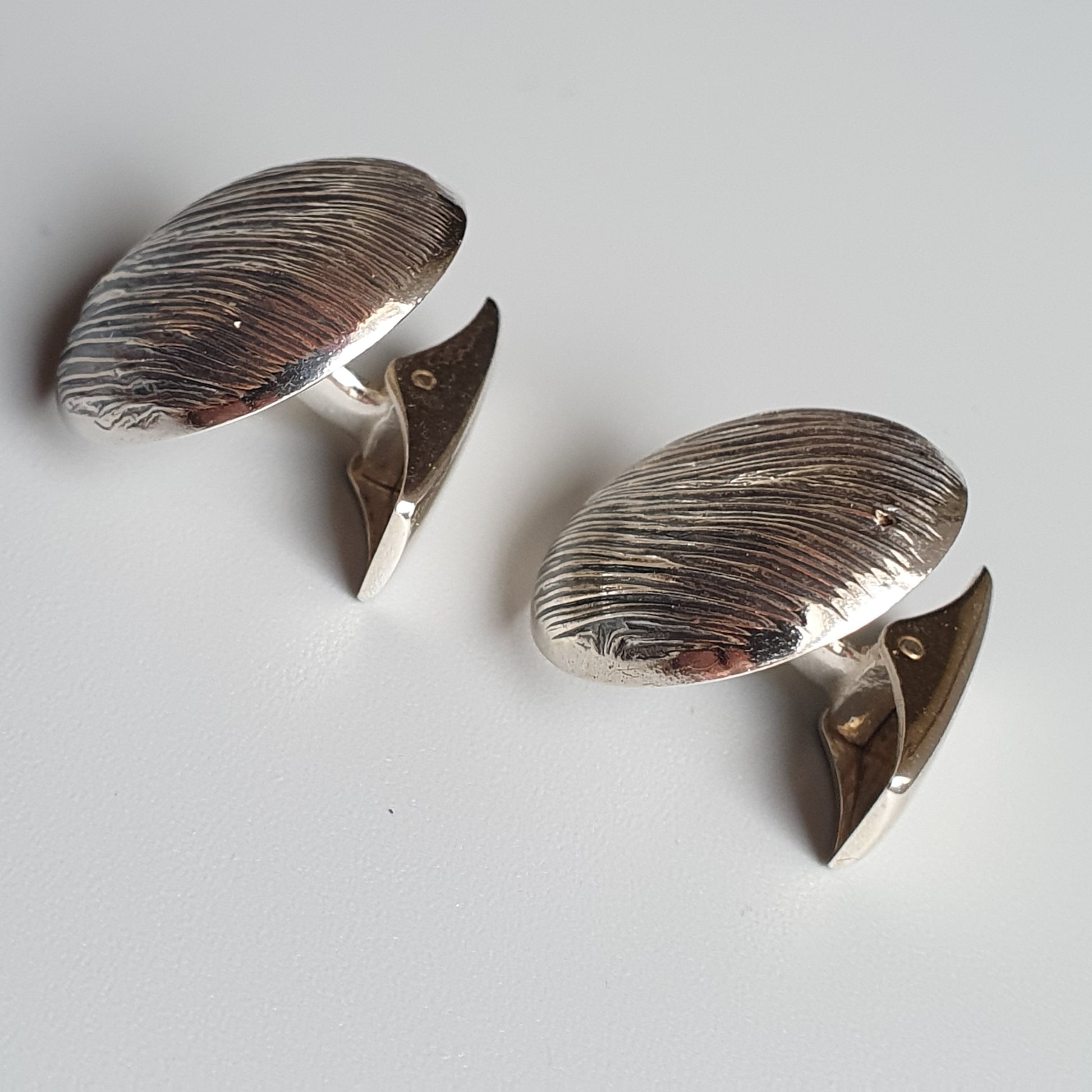 Pair of silver cufflinks shaped like mushrooms or toadstools.