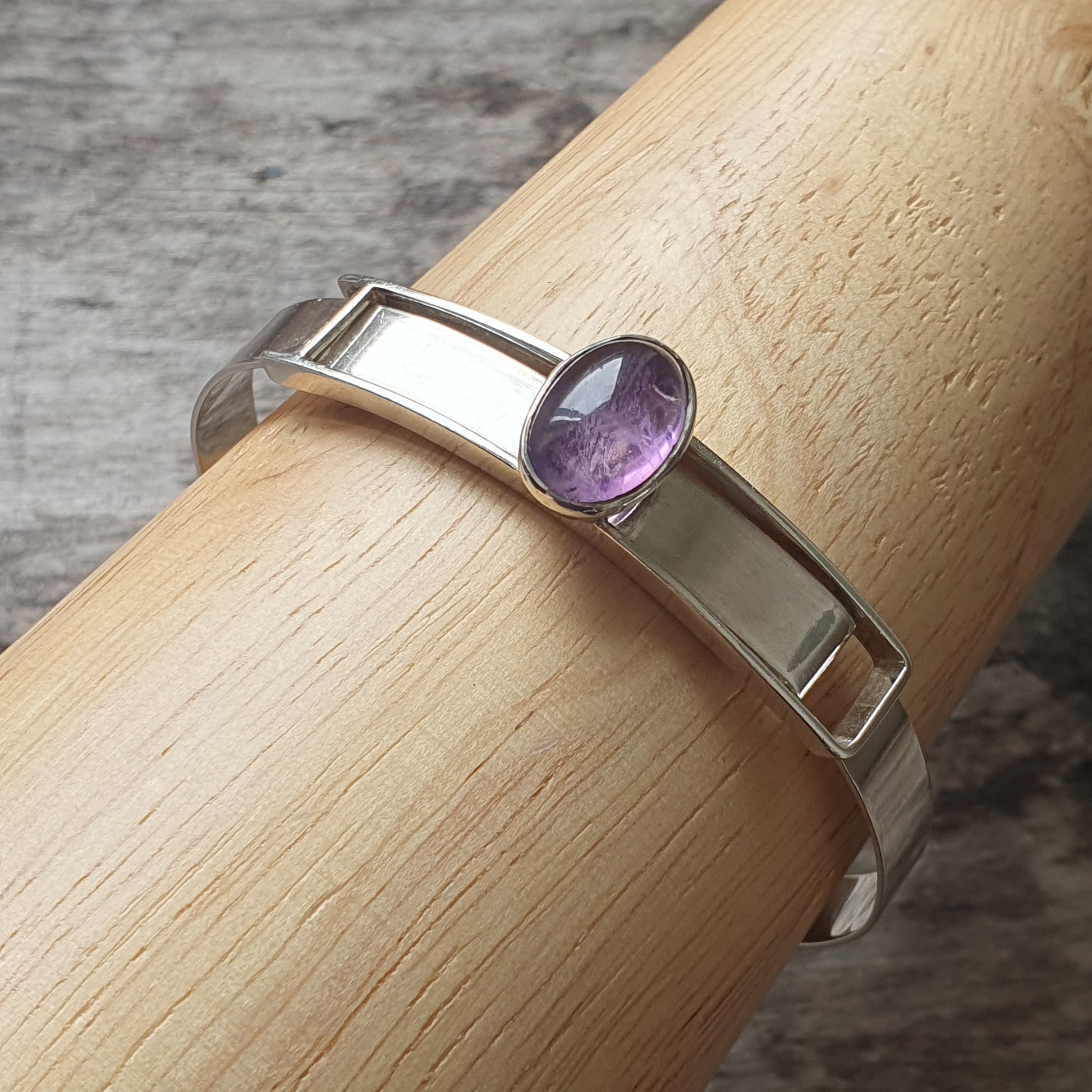 Silver ring with a small oval purple gemstone.