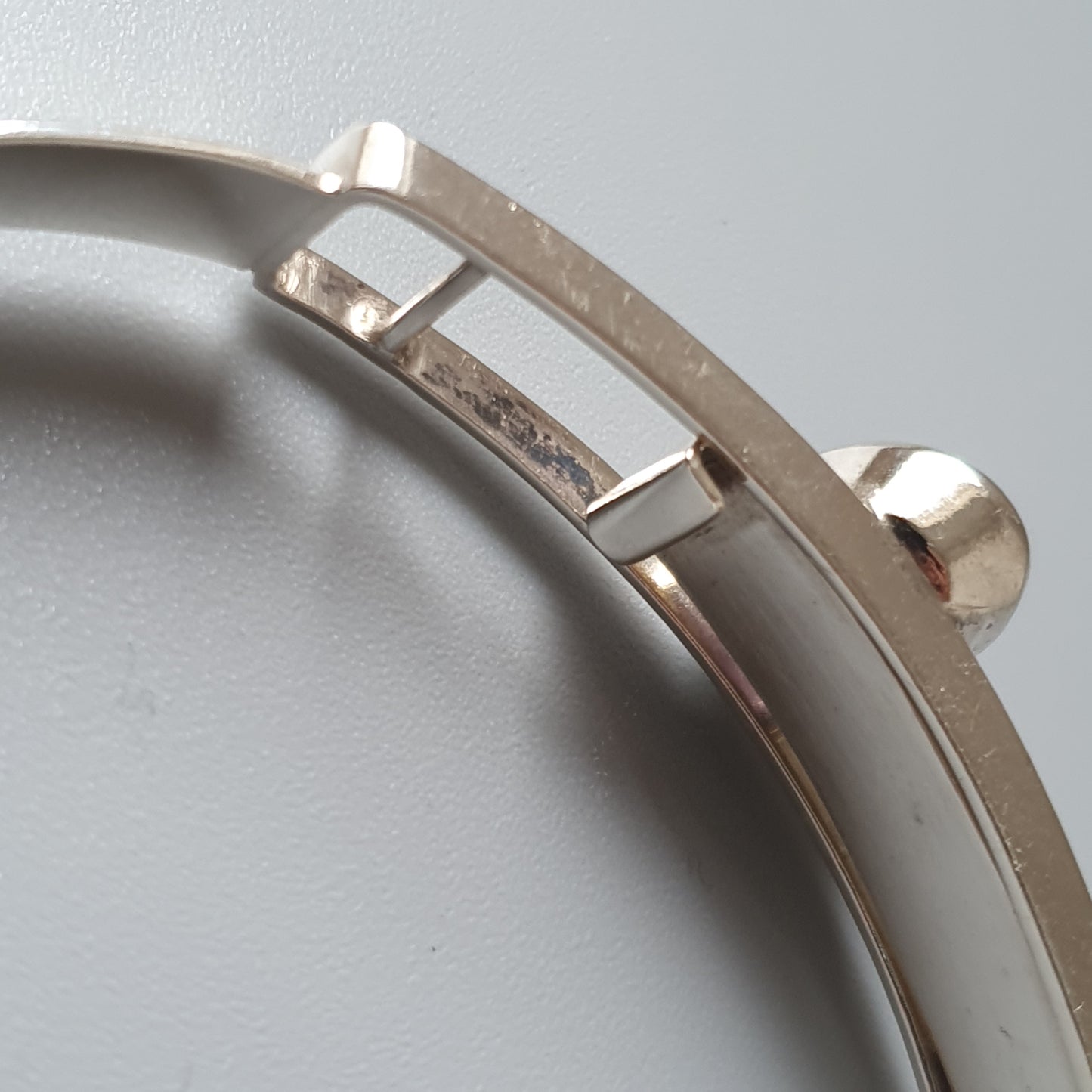 Curved metal watch bezel with a rectangular cutout.