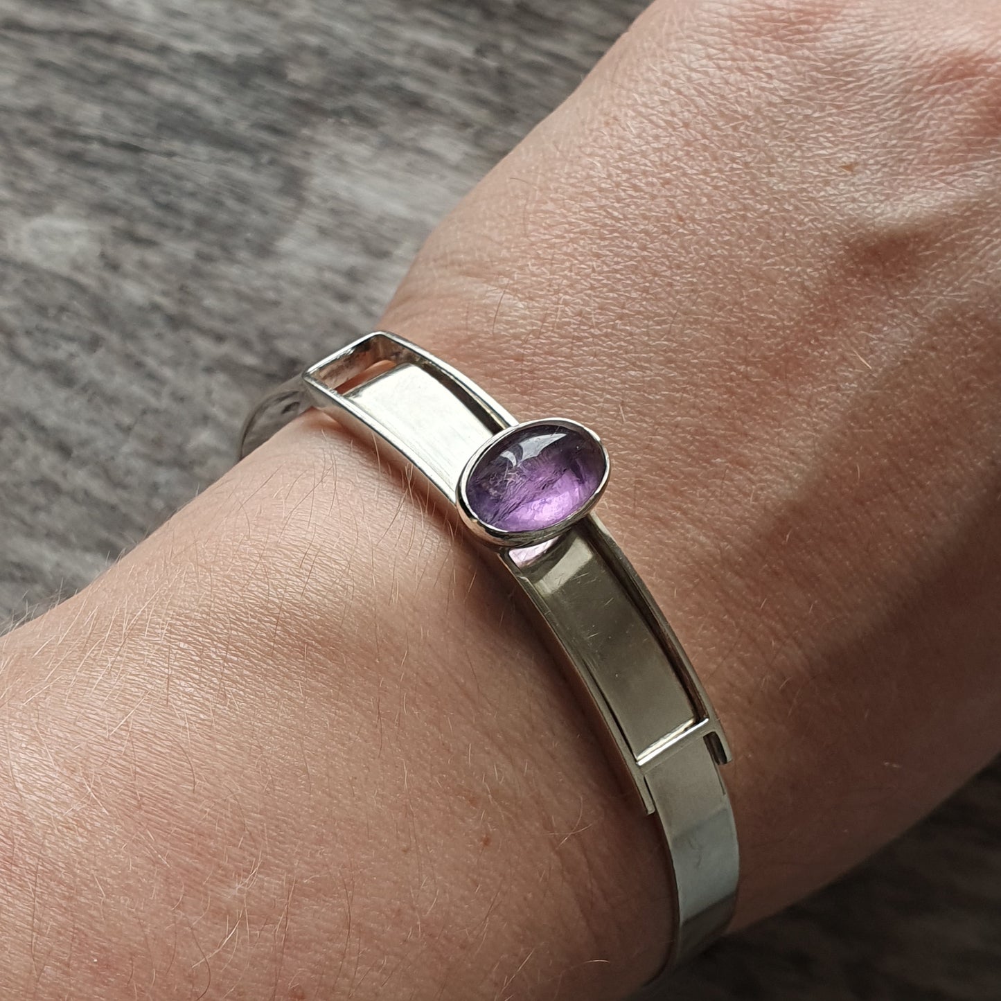 Silver bracelet with a purple gemstone.