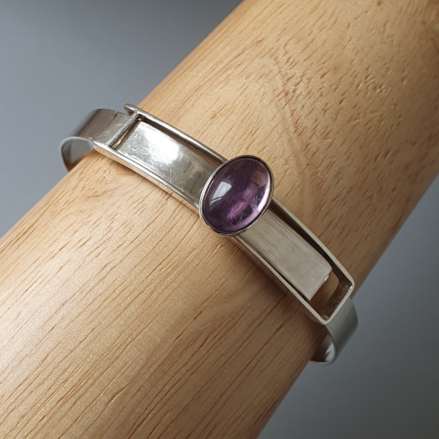 Silver bracelet with a purple gemstone.