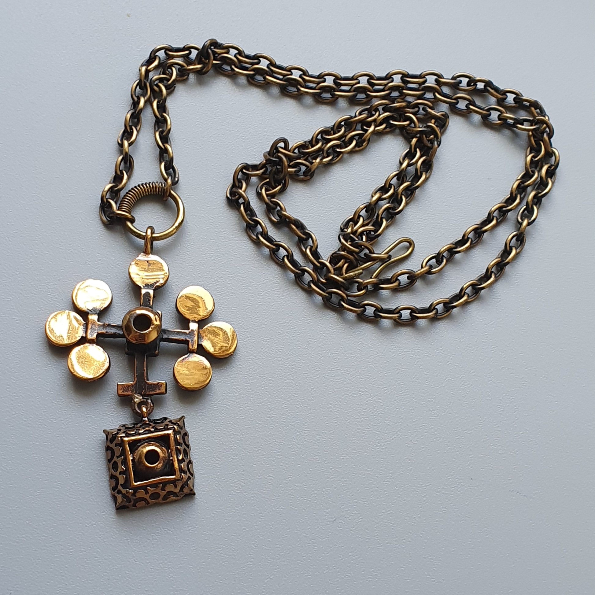 Ornate cross pendant necklace with gold-colored accents on an antique-style chain.