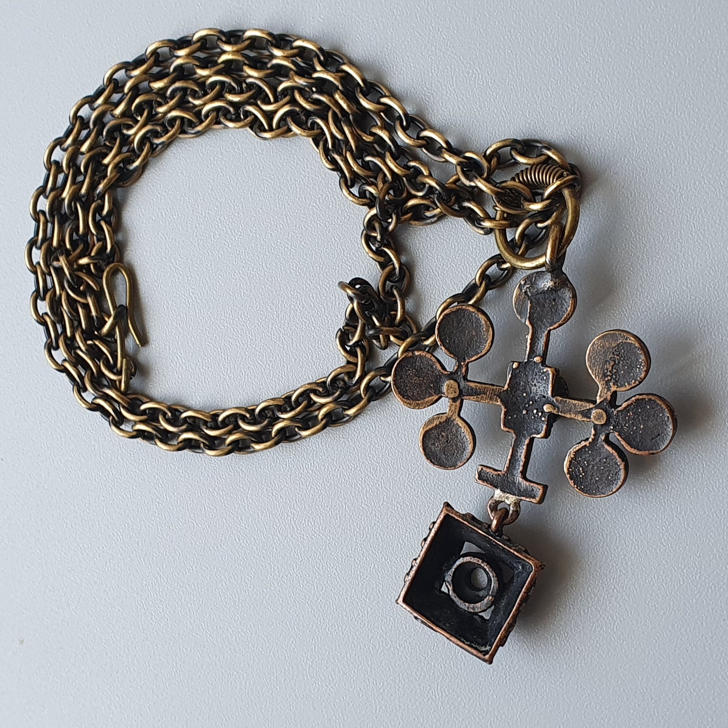 Antique-style metal chain bracelet with decorative cross and square charms attached.