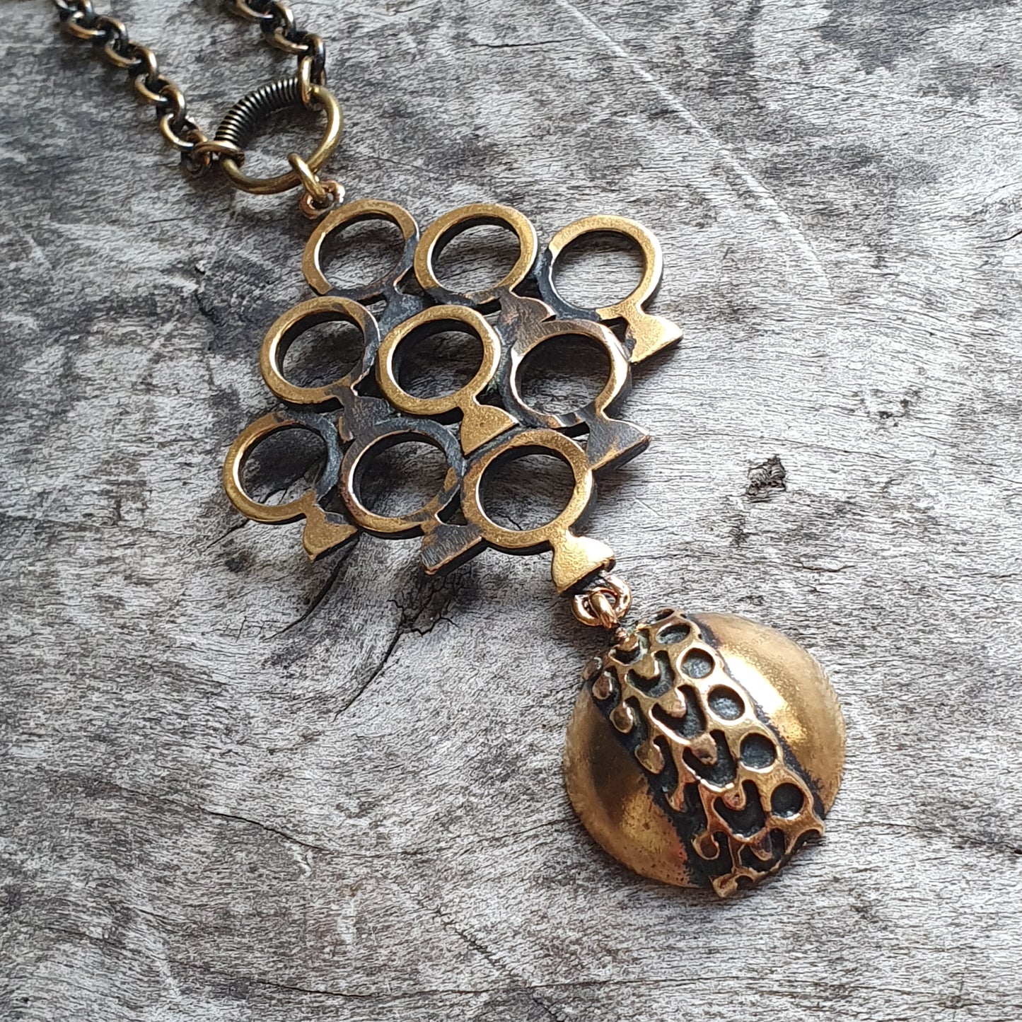 Brass pendant necklace featuring a geometric design of interconnected circles and a dangling circular charm.