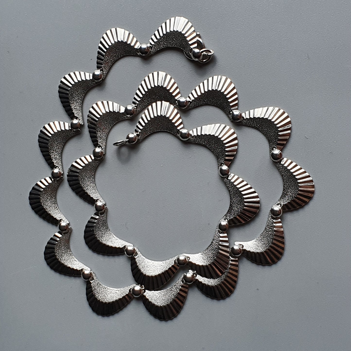 Ornate silver necklace with a scalloped, wavy design.