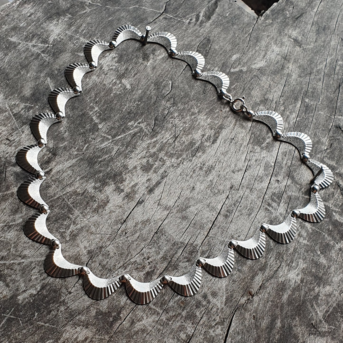 Silver necklace with scalloped shell-like shapes forming its design.