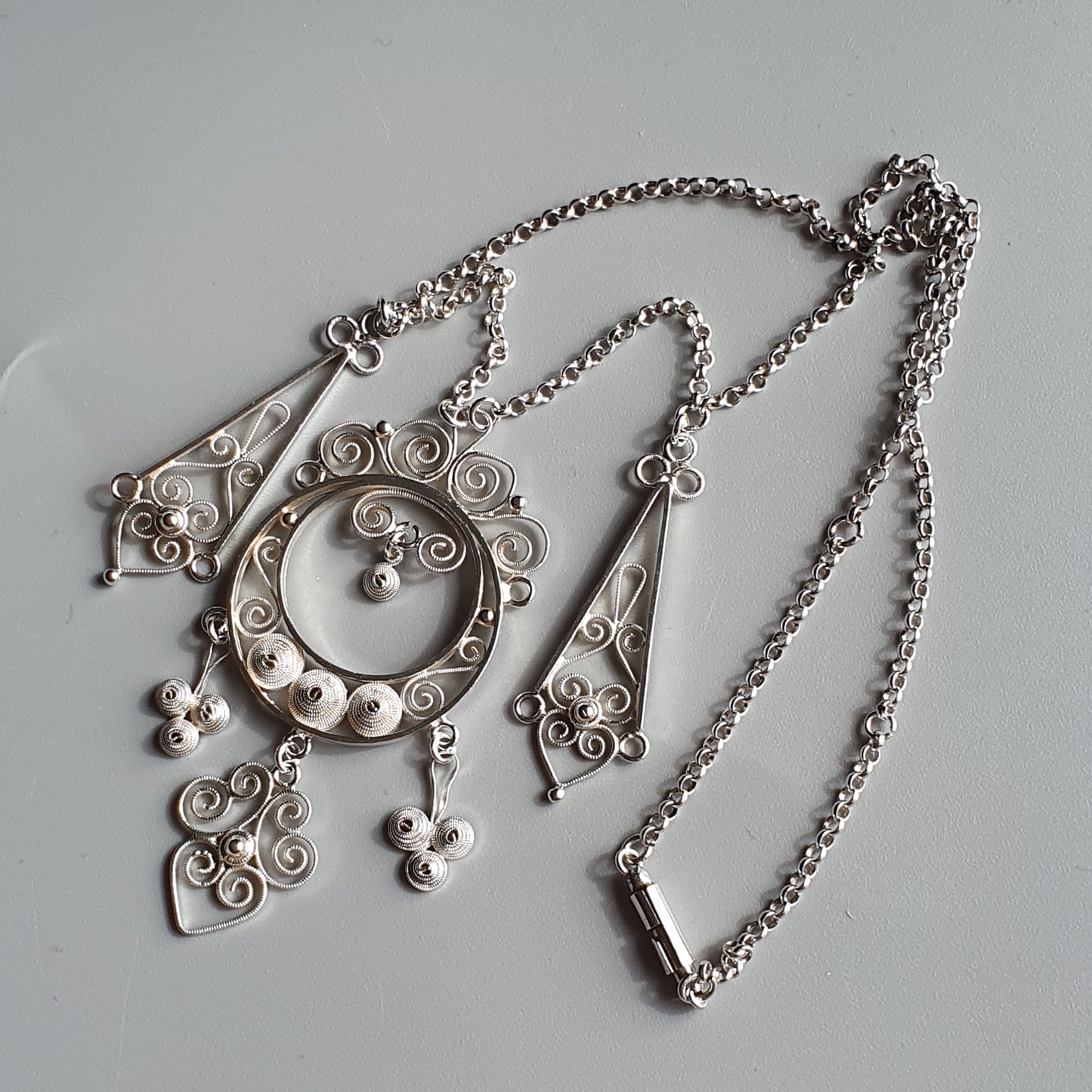 Ornate silver necklace with intricate filigree and circular pendant designs.