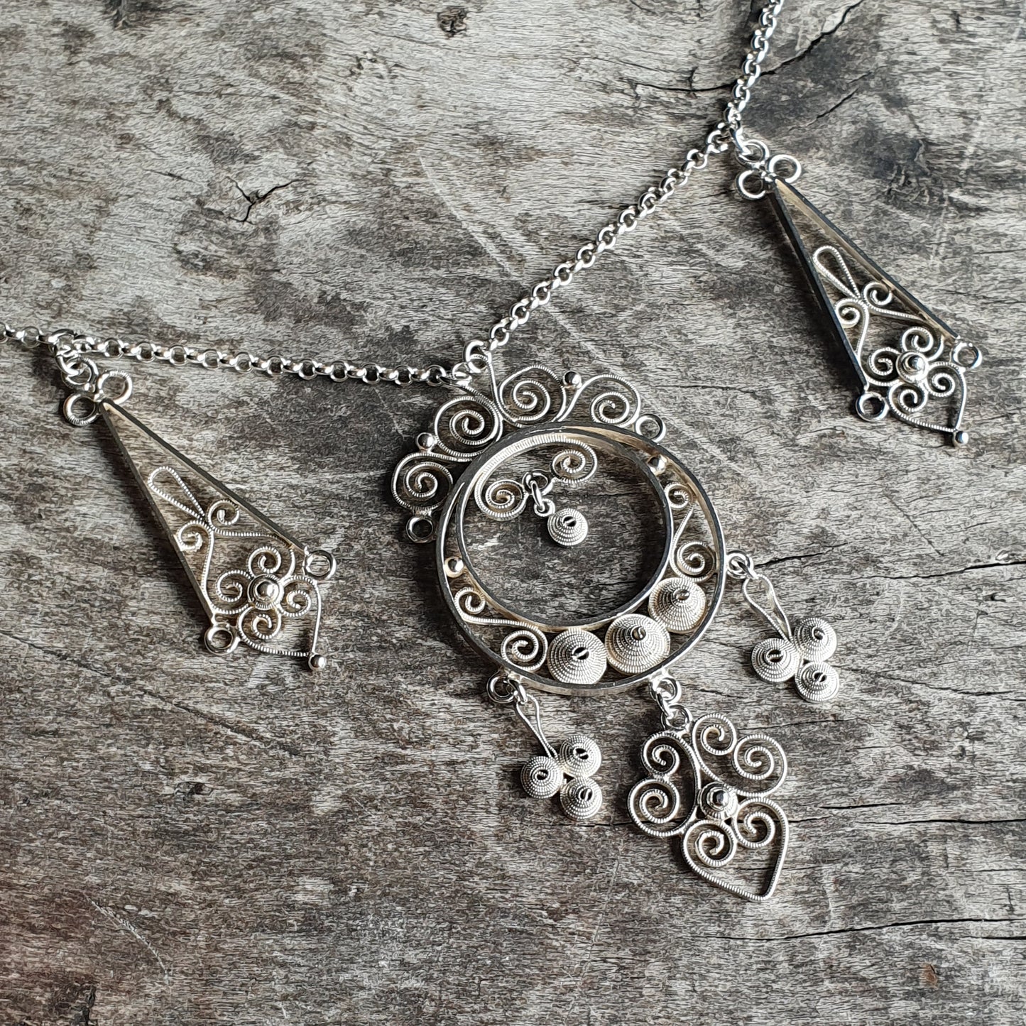 Ornate silver necklace with intricate filigree pendant and matching earrings.