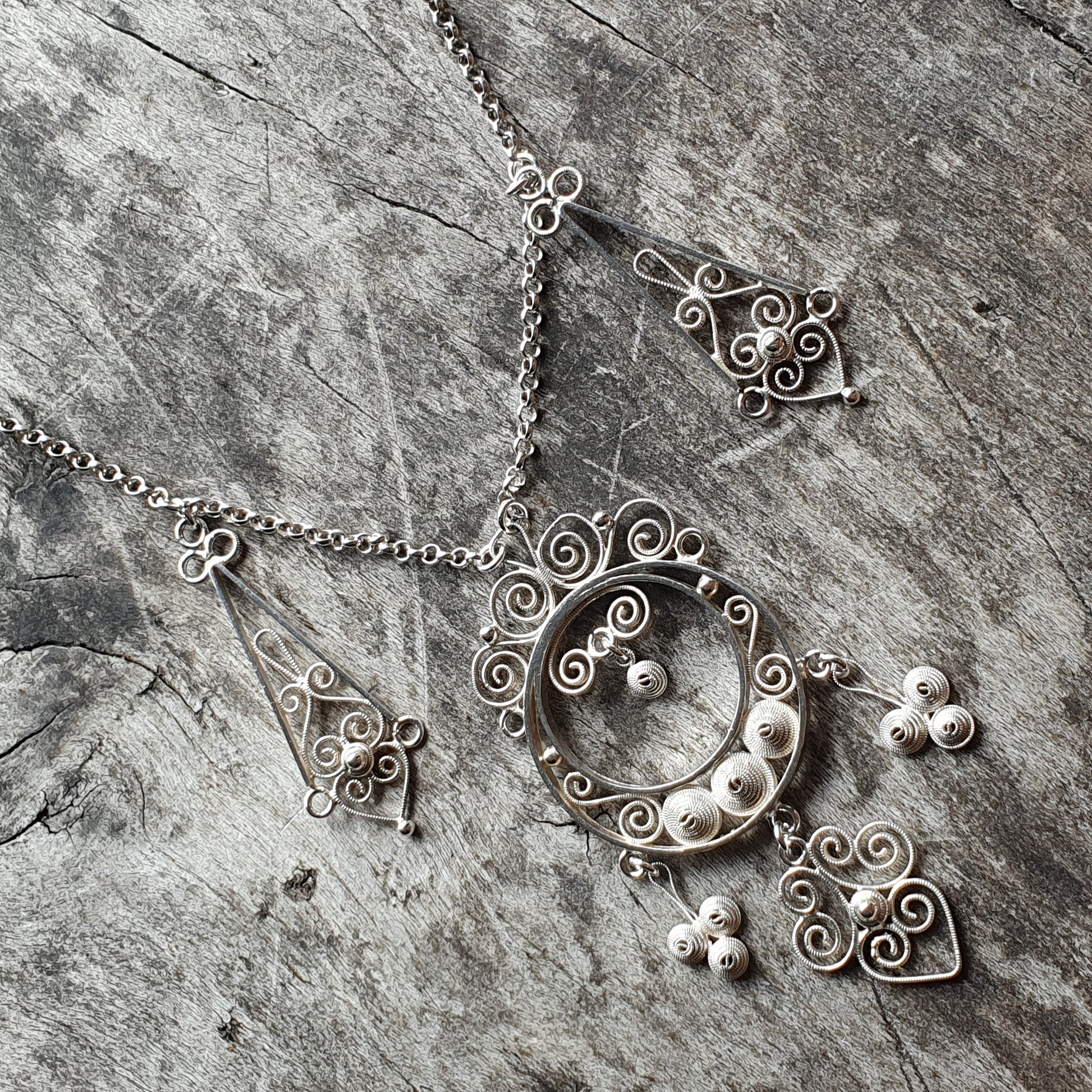 Ornate silver necklace with a crescent moon pendant featuring intricate swirls and beads.