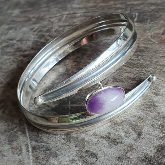 Silver bracelet with a purple gemstone accent in a modern, curved design.