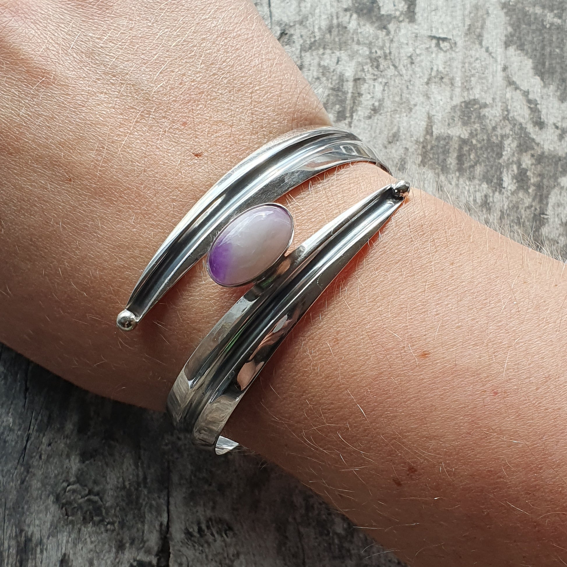 Silver bracelet with a purple oval stone or gem accent.