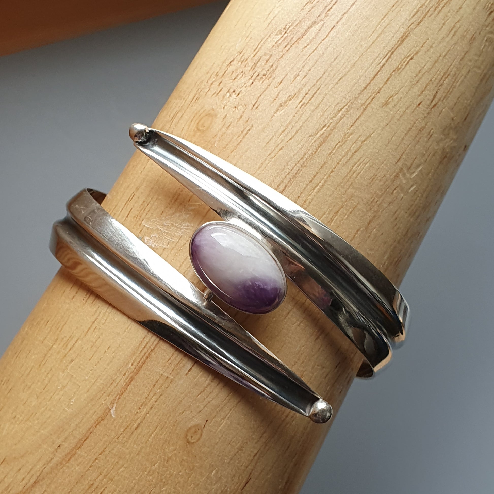 Silver ring with multiple bands and a small oval purple gemstone.