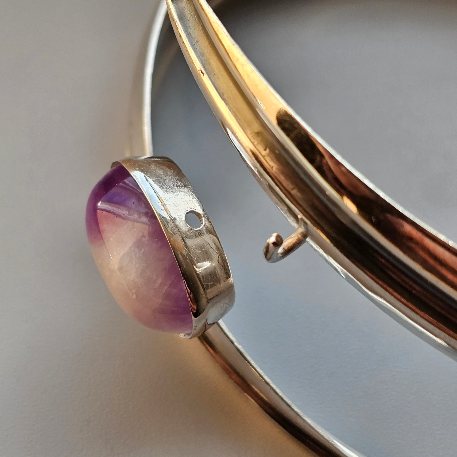 Silver bracelet or bangle with a purple gemstone setting.