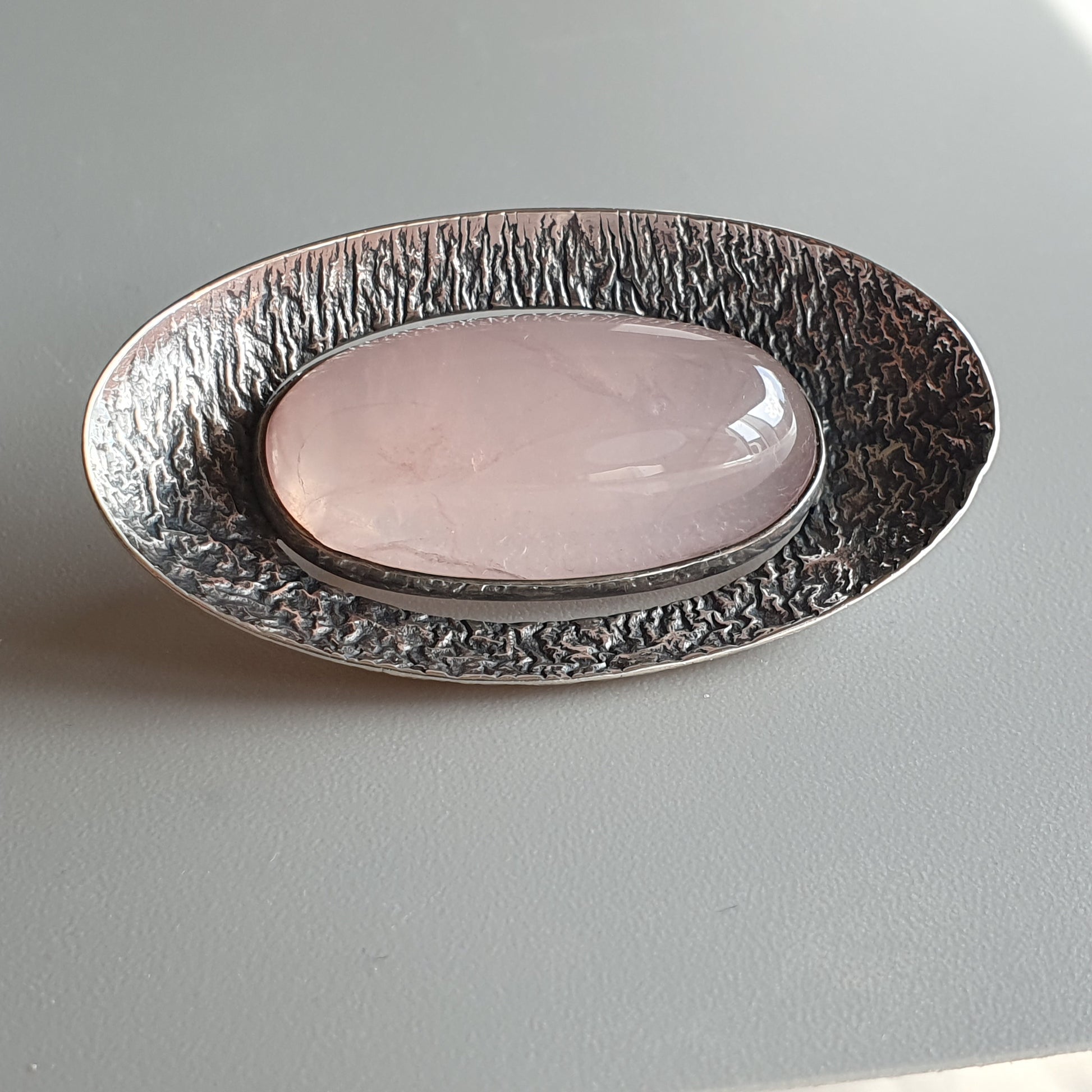 Oval dish with a textured metallic rim and smooth pink center.