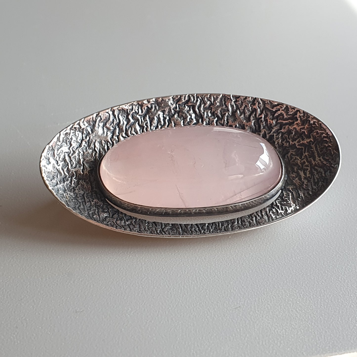 Oval-shaped metallic dish with a textured rim and smooth pink center.