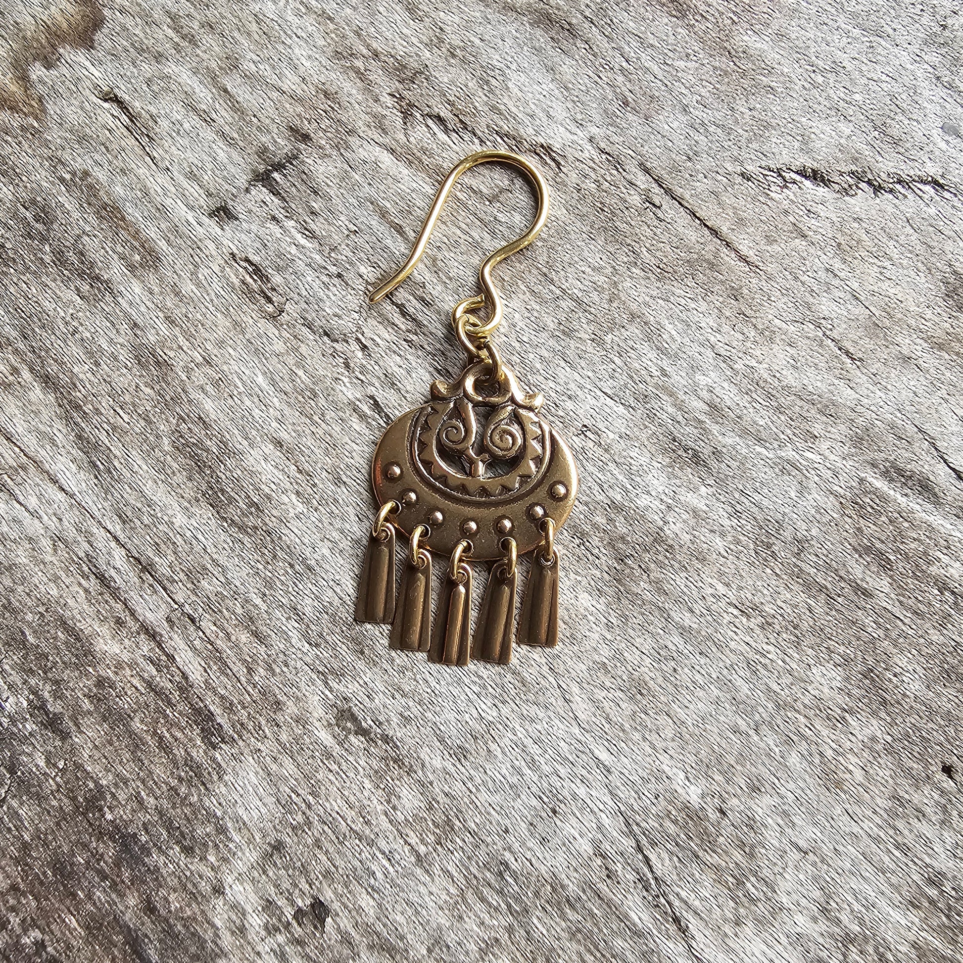 Gold-toned ornate earring with a circular design and dangling fringes.