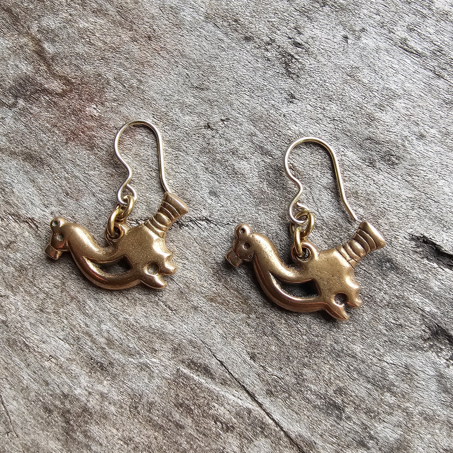 Pair of gold-colored earrings shaped like stylized horses or unicorns.