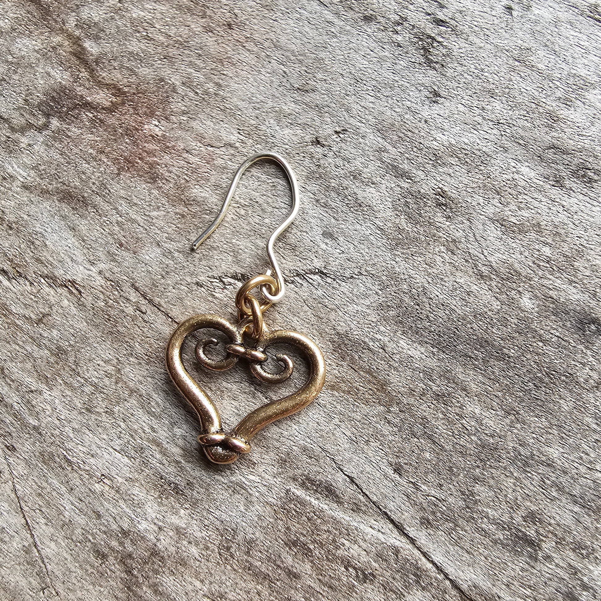 Heart-shaped gold-toned earring with a curled wire design.