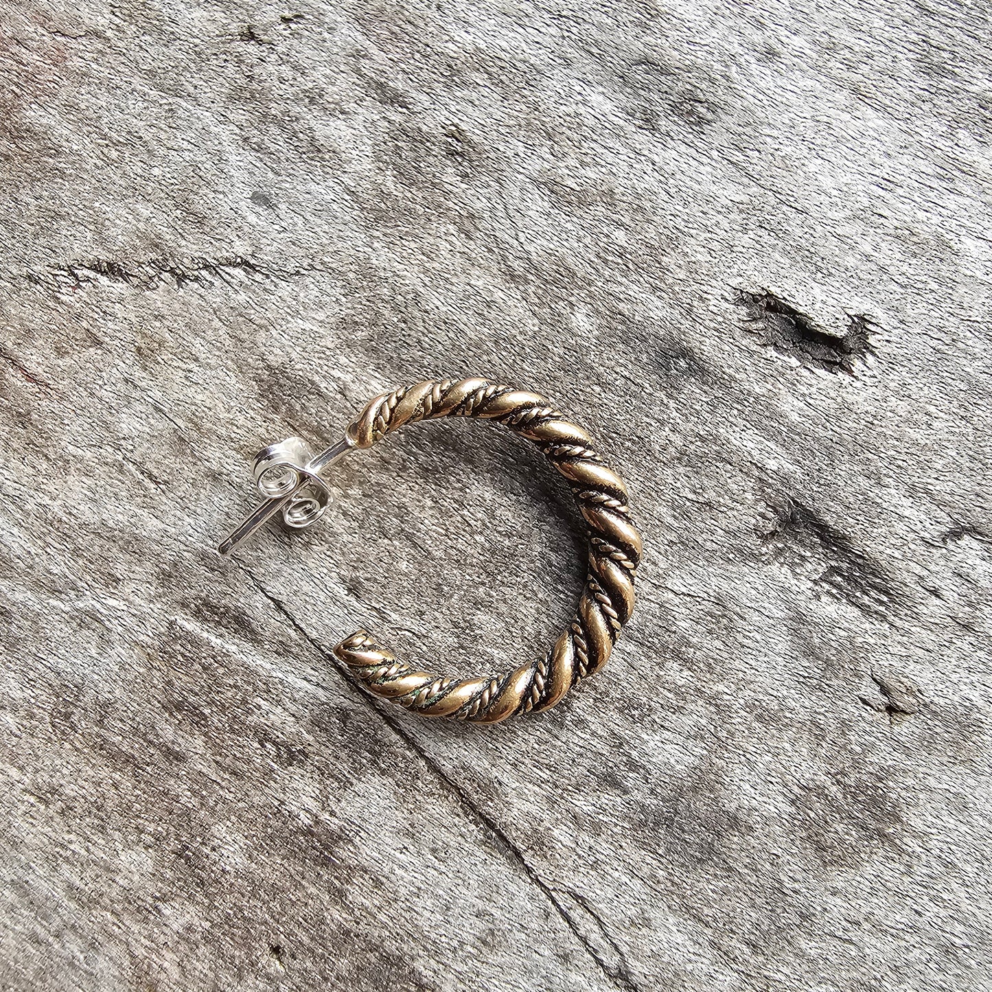 Twisted metal hoop earring with a rope-like texture.