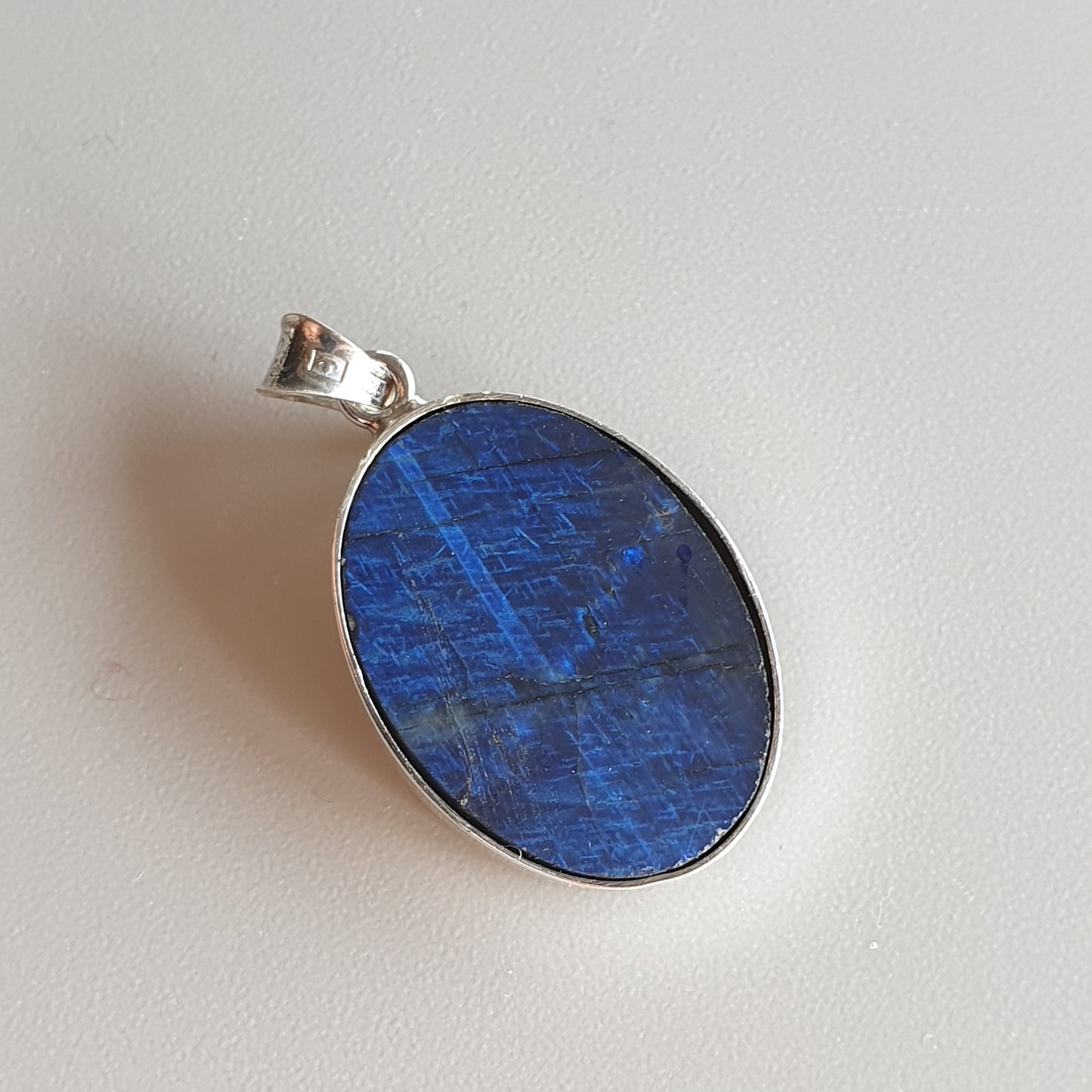 Oval blue gemstone pendant set in silver.