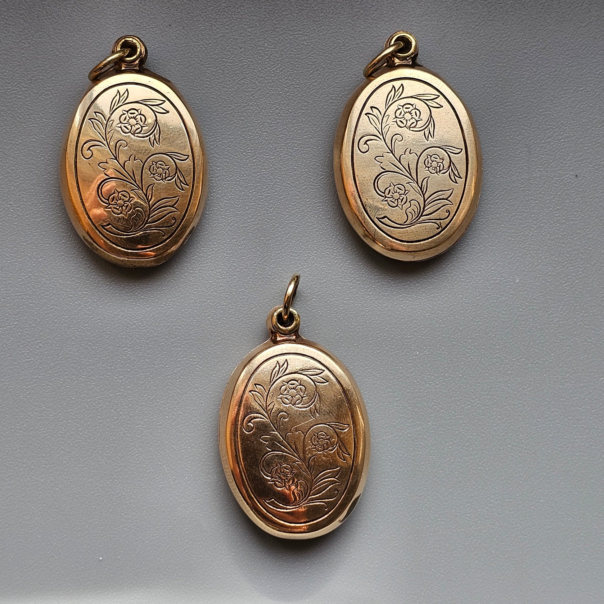 Gold oval lockets with engraved floral designs.