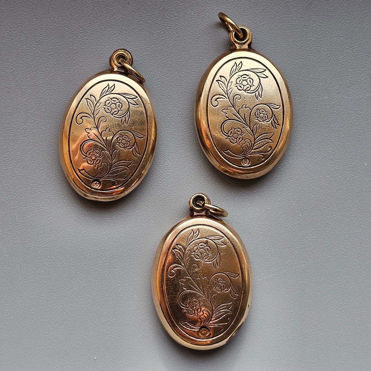 Gold oval lockets with engraved floral designs.