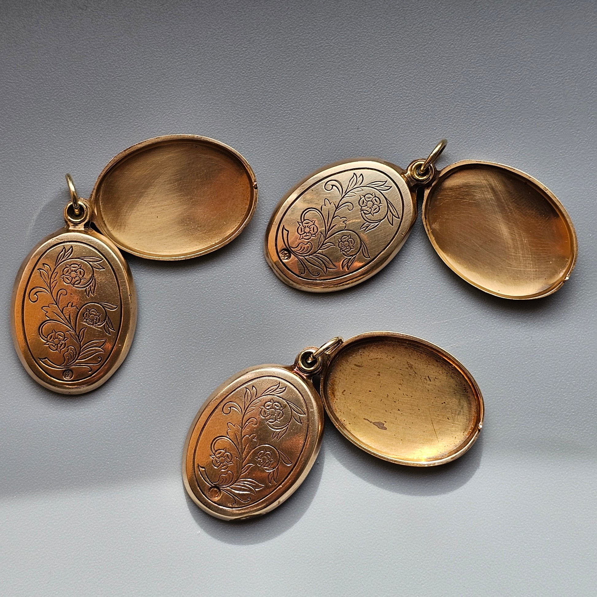 Vintage gold-toned oval lockets with engraved floral designs.