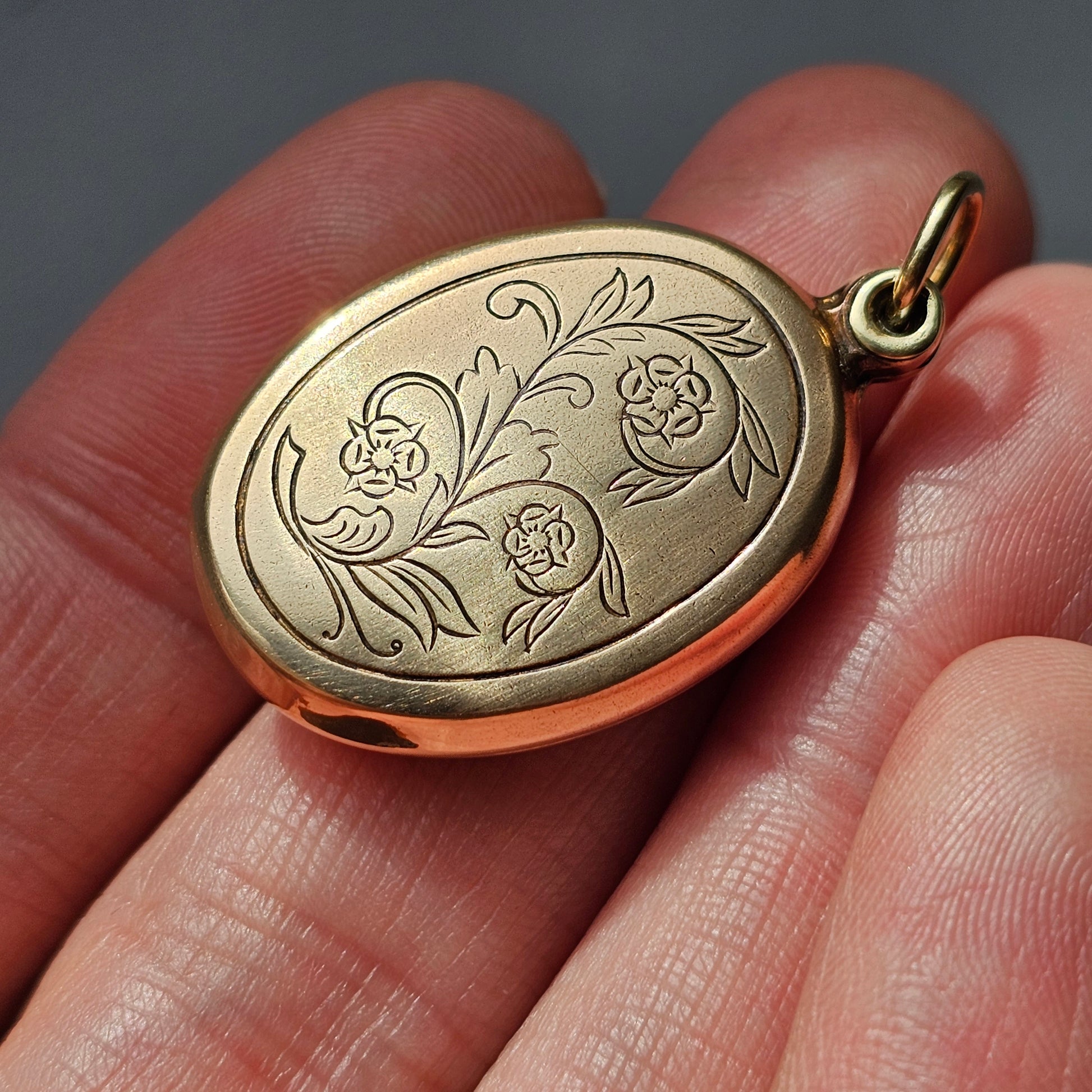 Gold oval locket with an engraved floral design.