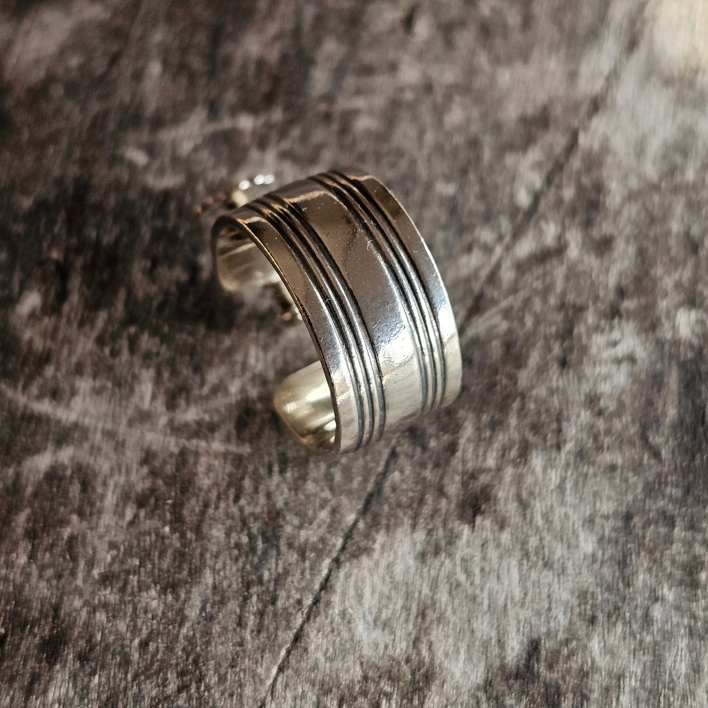 Silver ring with multiple parallel grooves around its circumference.