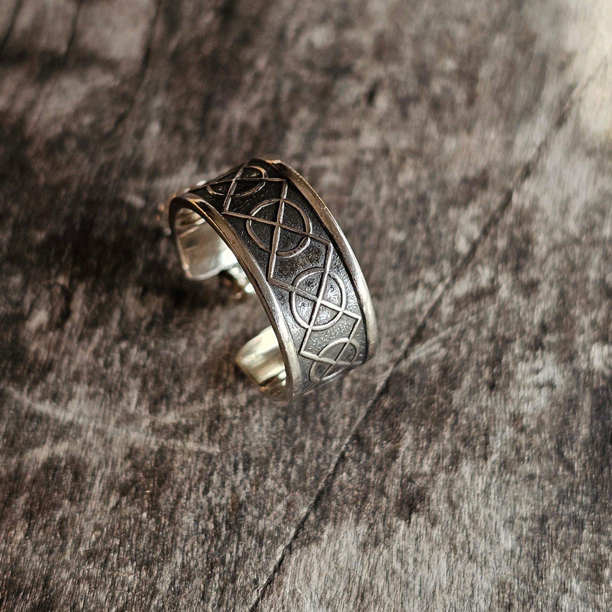 Silver ring with an intricate geometric pattern engraved on its surface.