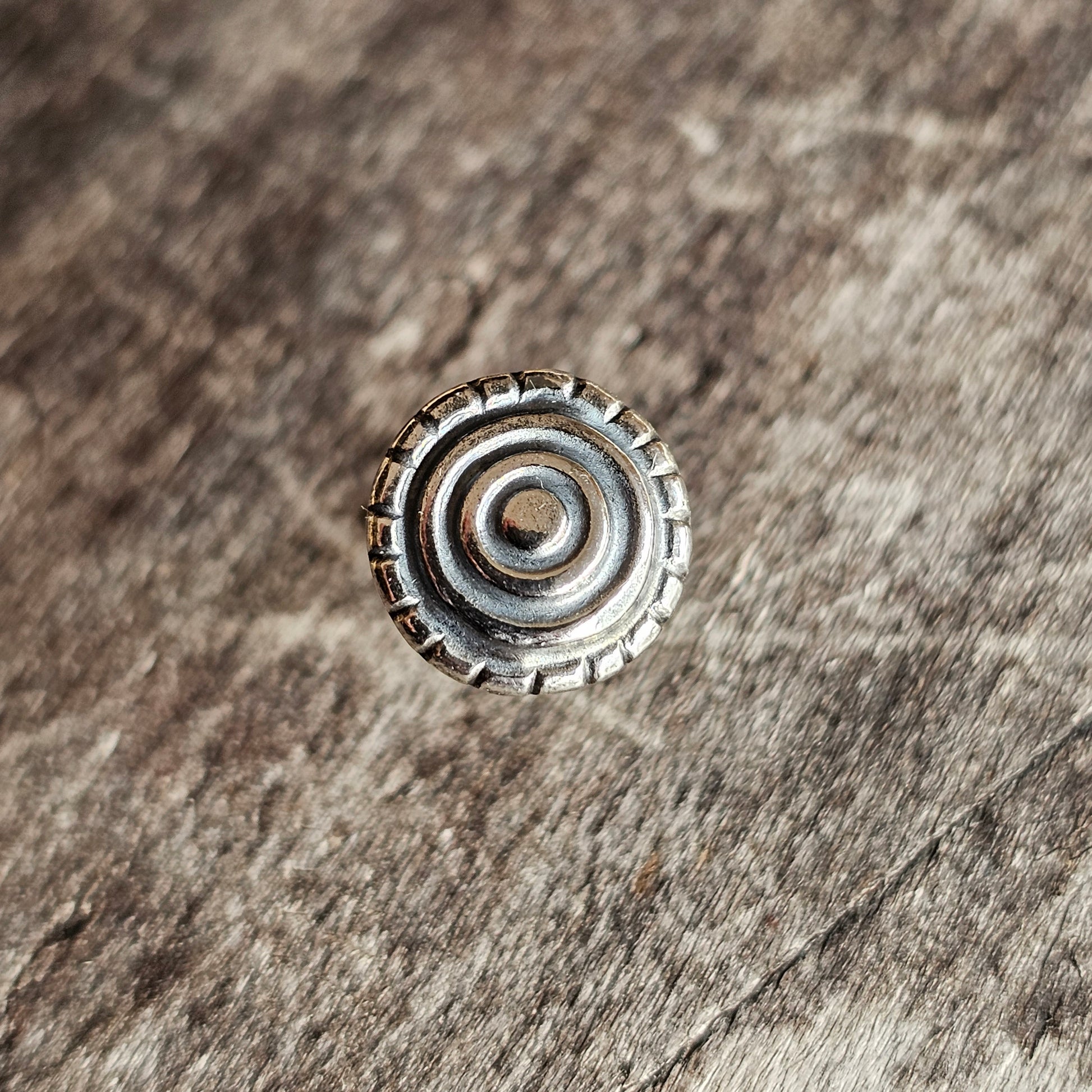 Metallic bottle cap with concentric circular ridges on its top surface.