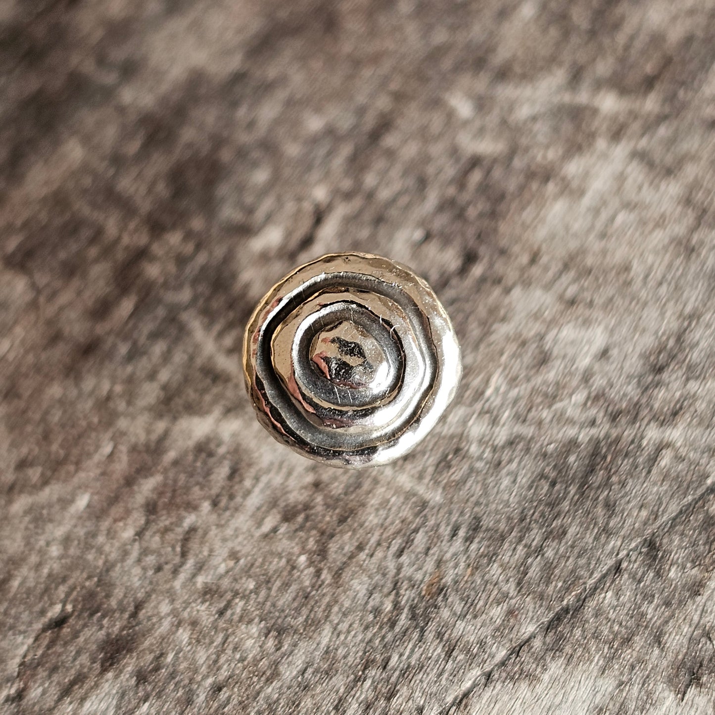 Silver spiral-shaped metal stud or button.