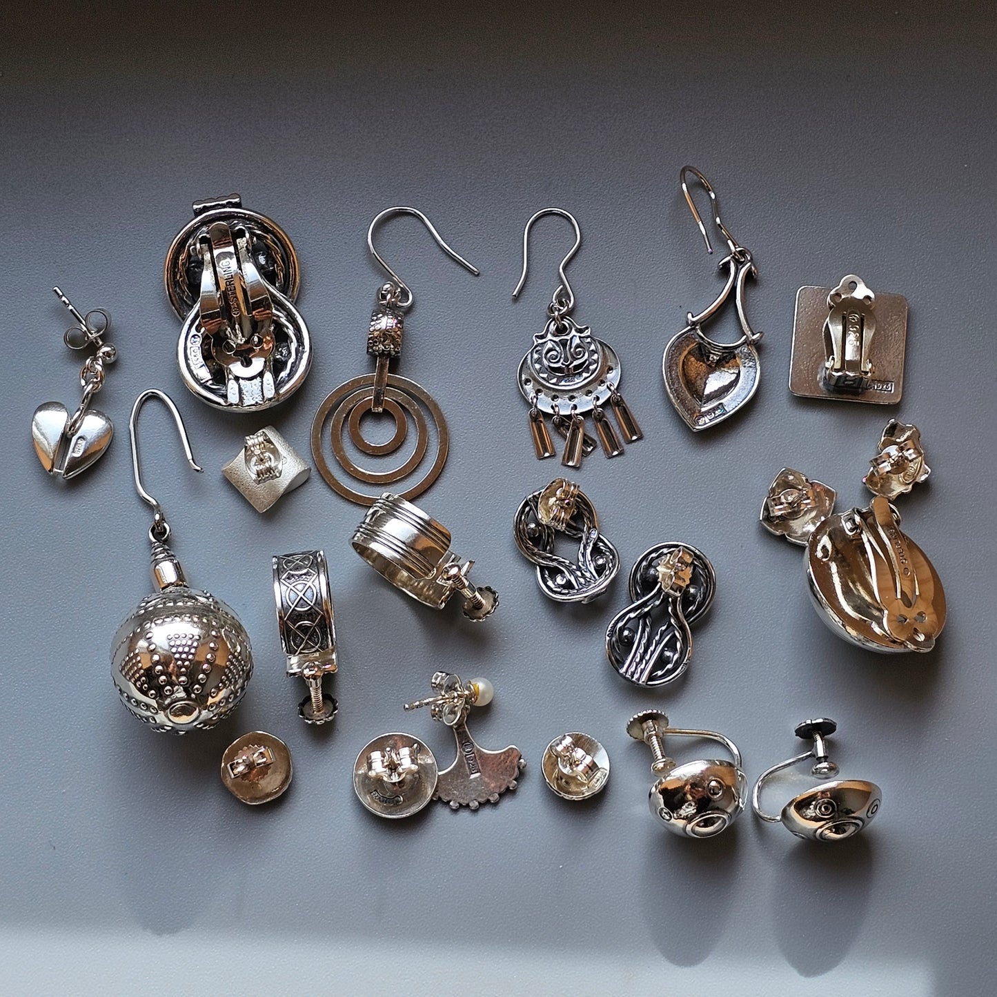 Collection of various silver and gold-toned jewelry pieces and charms laid out on a surface.