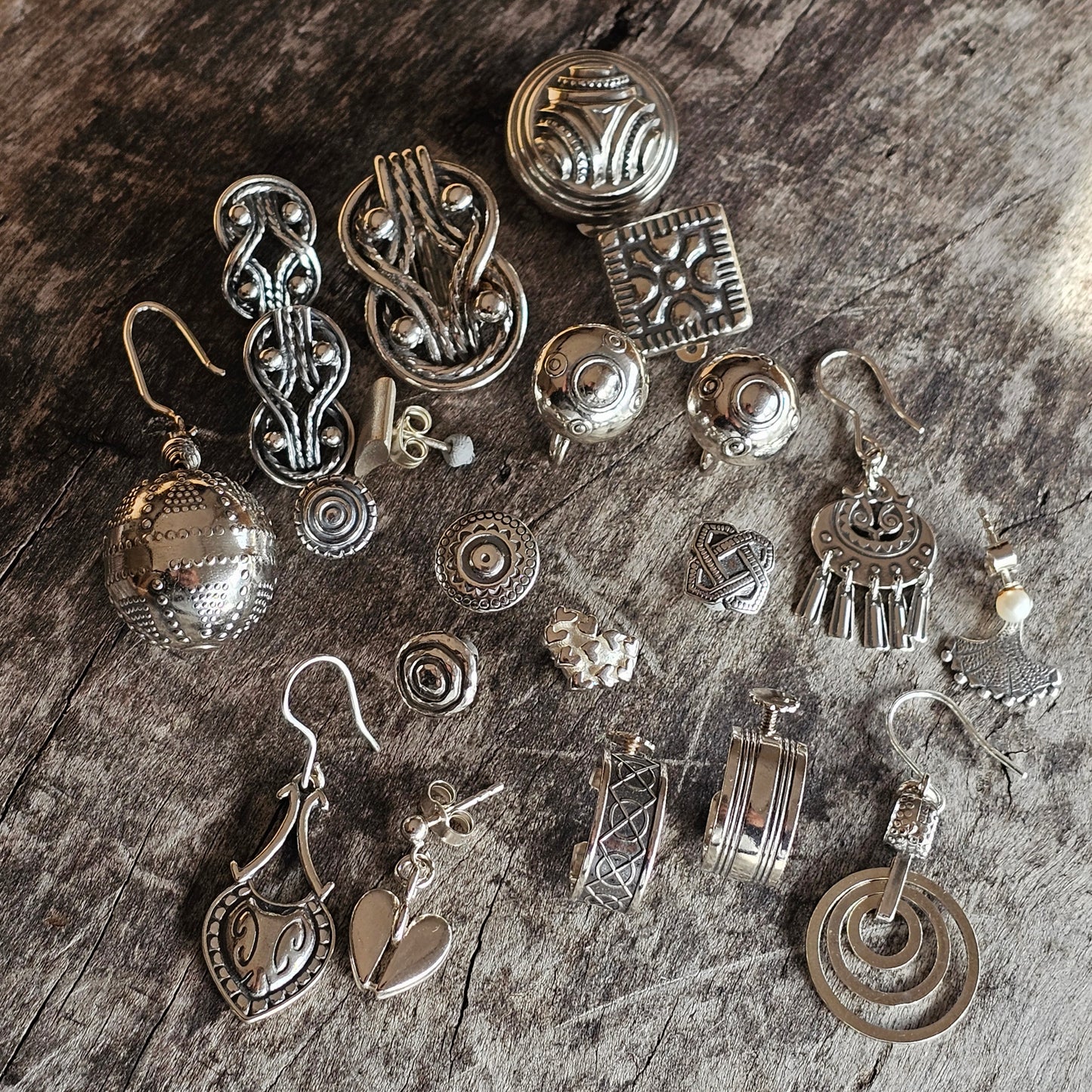 Collection of silver-toned jewelry pieces and ornaments with various designs and shapes.