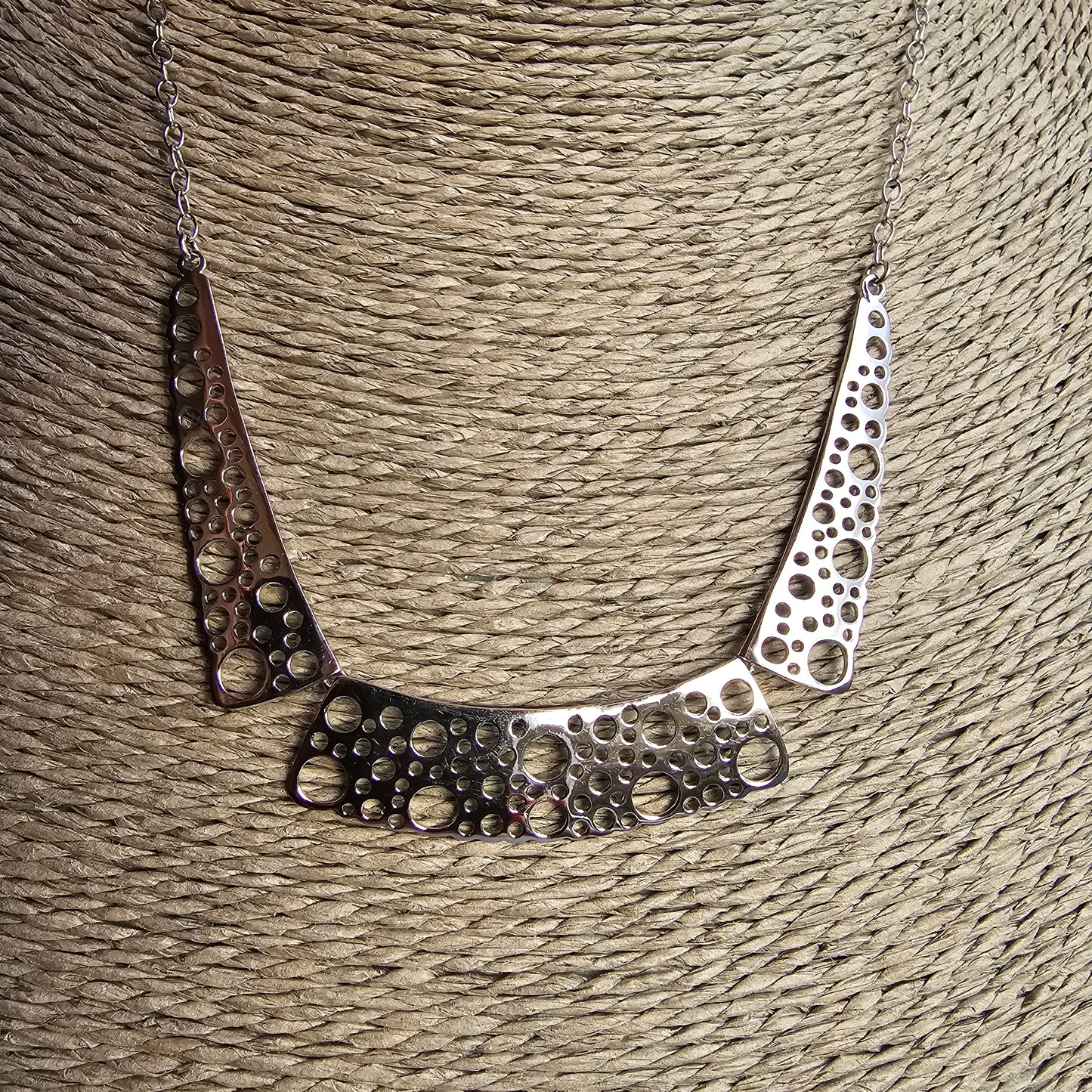 Silver necklace with perforated geometric design elements.